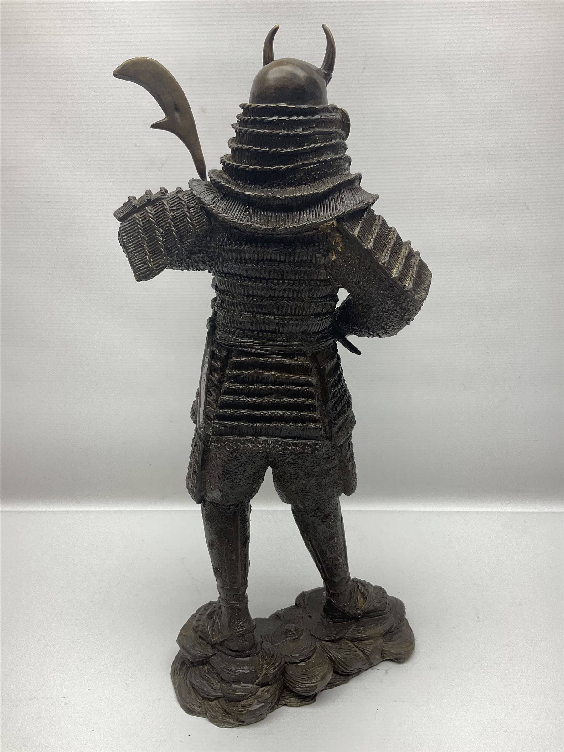 Bronze figure of a samurai standing wearing armour and holding a naginata, upon a rocky base, H48cm