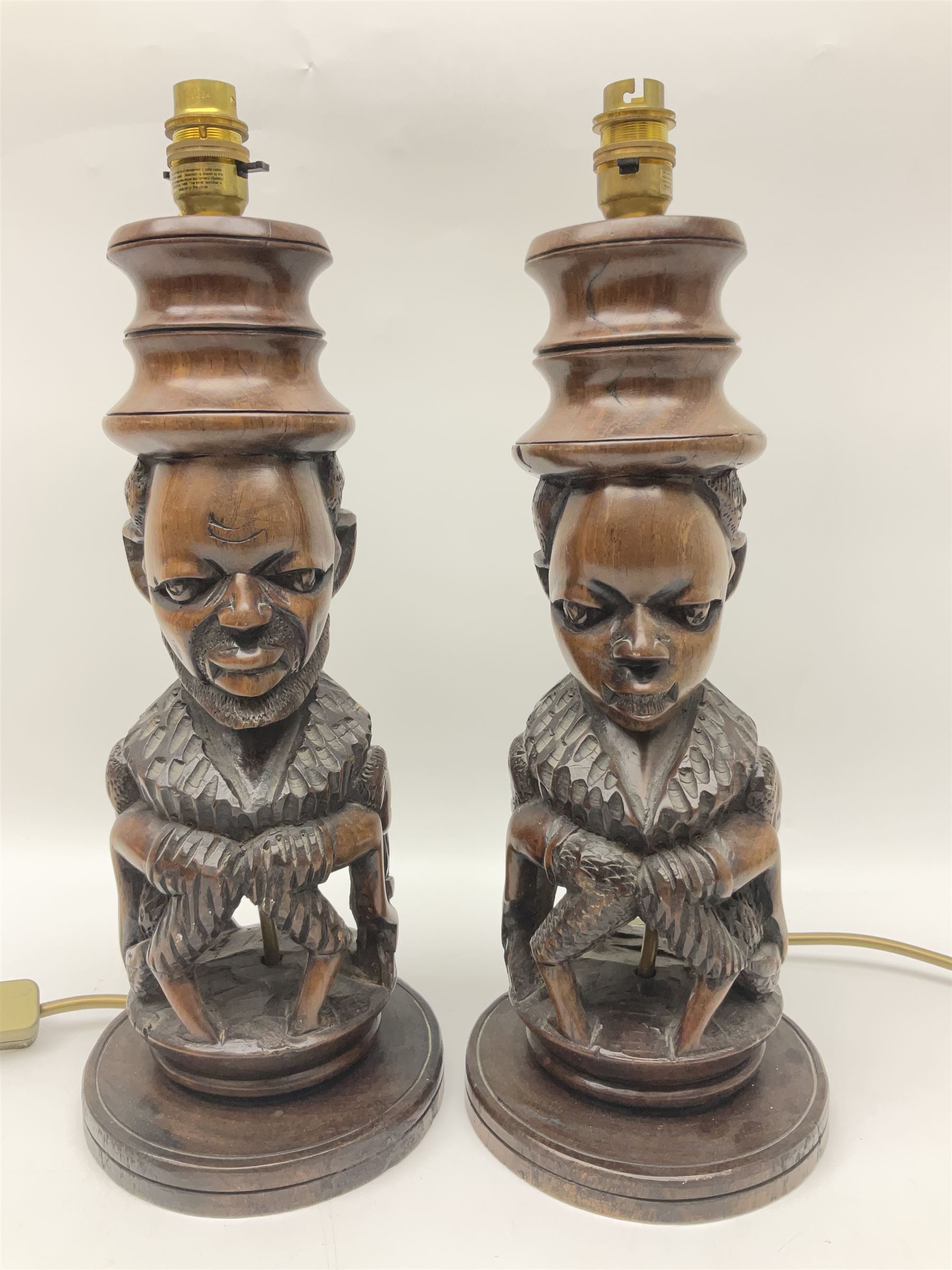 Pair of 20th century carved wood table lamp with African busts and figures, together with a carved wooden figure and soapstone figure, lamps H44cm