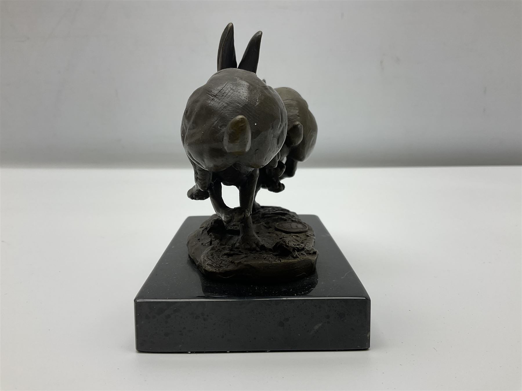 Bronze figure group, modelled as two hares in chase, upon a naturalistic base signed Nick and with foundry mark, raised upon a rectangular marble base, overall H12cm. 