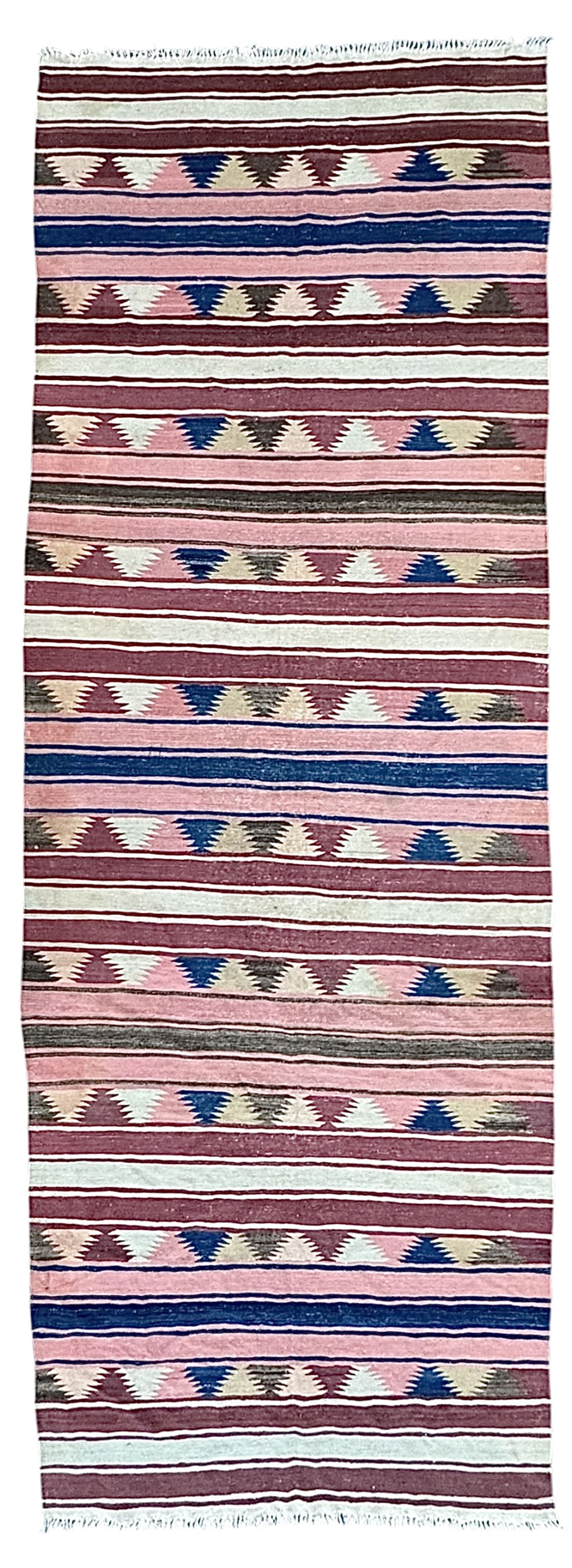 Kilim muted pink ground runner, decorated with rows of horizontal bands in muted tones, alternating with geometric triangular patterns along each band, fringed ends