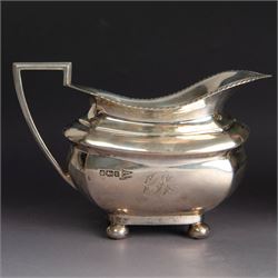 Early 20th century three piece silver tea service, comprising teapot, open sucrier and milk jug, all with oblique gadrooned rim, engraved initial to body and upon four bun feet, the teapot with Bakelite type handle and finial, hallmarked Walker & Hall, Sheffield 1912, contained within an oak presentation case with silk lining