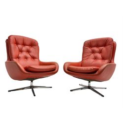 Pair mid-20th century circa.1974 swivel lounge chairs upholstered in buttoned red faux leather, on polished metal base