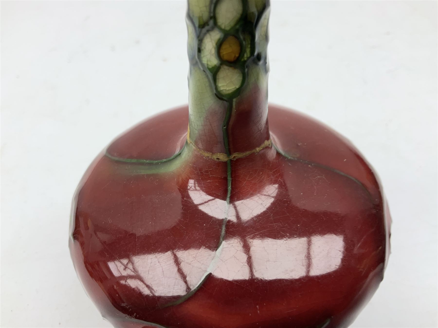 Three Minton Secessionist vases, with tube-lined stylised flower decoration, two upon a red ground and third upon a purple ground, all with printed mark to base 'Minton Ltd, No. 33', H13cm