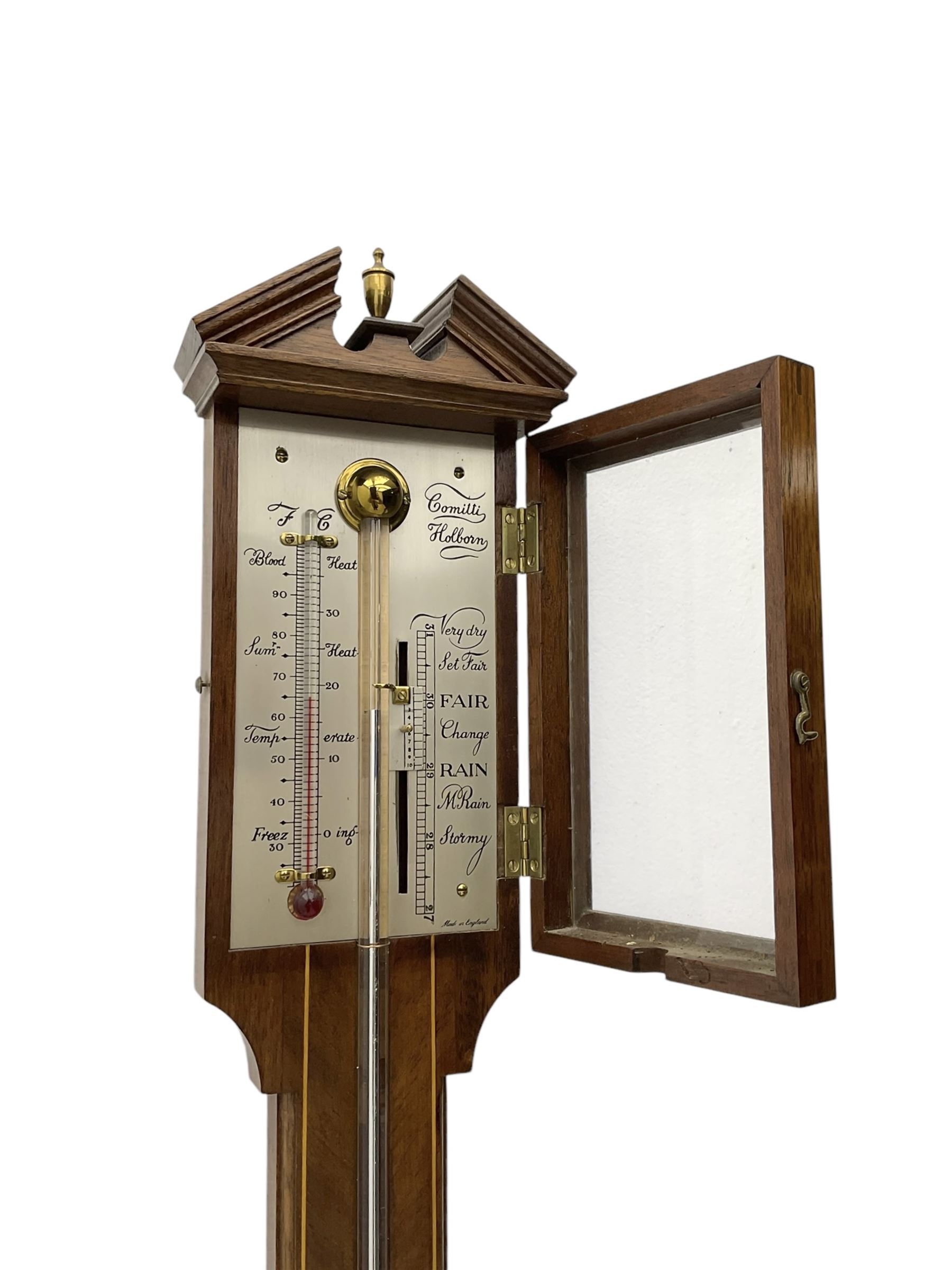 Comitti-20th century mercury stick barometer in an 18th century style mahogany case with satinwood stringing, with a broken pediment, brass finial and round base, silvered register with recording vernier, weather predictions and a centigrade/Fahrenheit spirit thermometer enclosed within a glazed door, visible tube with a bulb cistern and turned mahogany cover.
Mercury clean and present with no air locks.