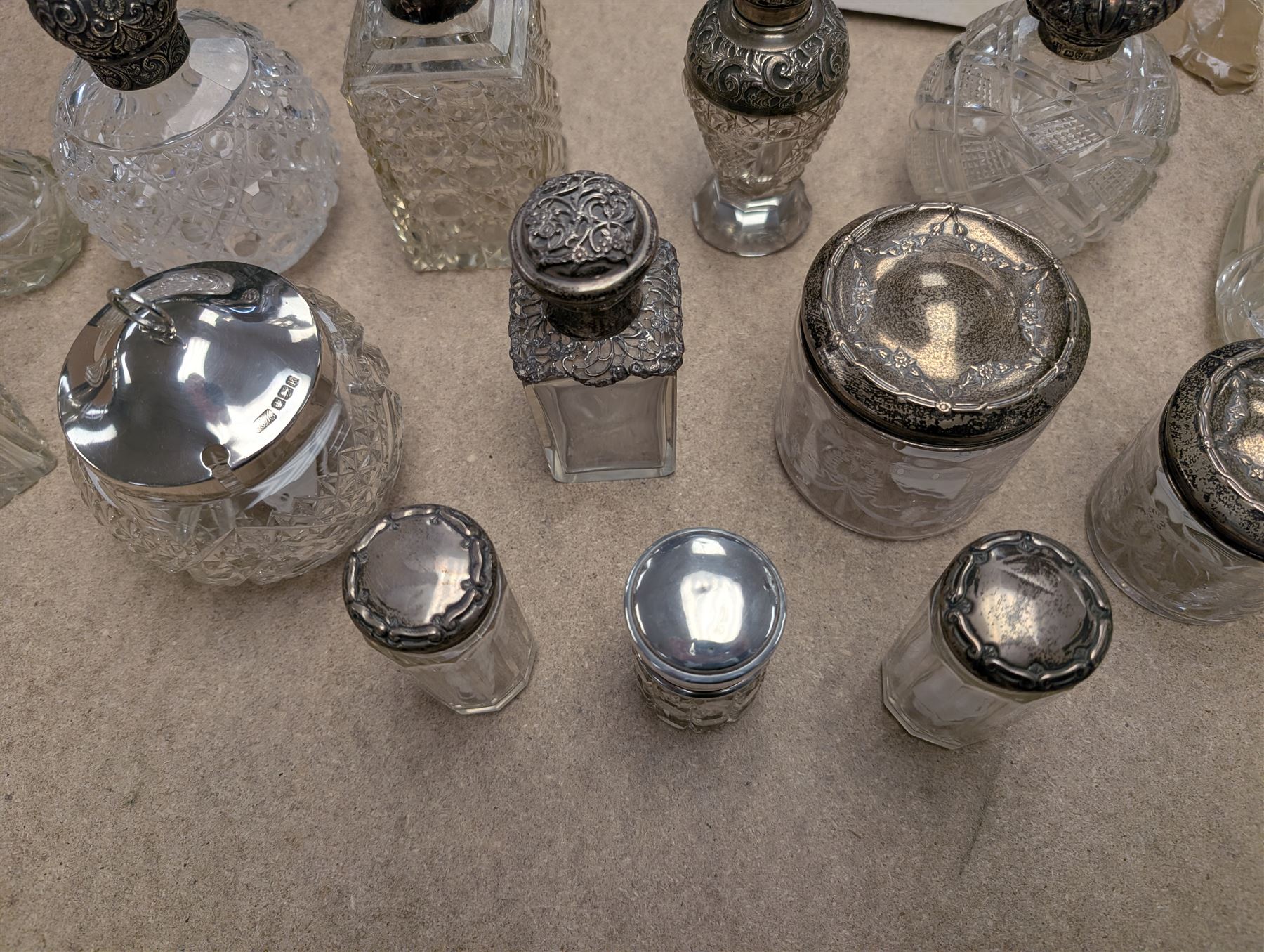 Collection of silver mounted glass bottles and jars, including decanter with etched floral decoration and silver collar, four scent bottles with silver caps, etc all hallmarked 