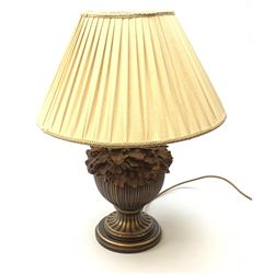 A composite wood effect table lamp, the reeded bulbous body detailed with oak leaves and acorns, upon spreading circular base, with pleated beige fabric shade, overall H58.5cm.