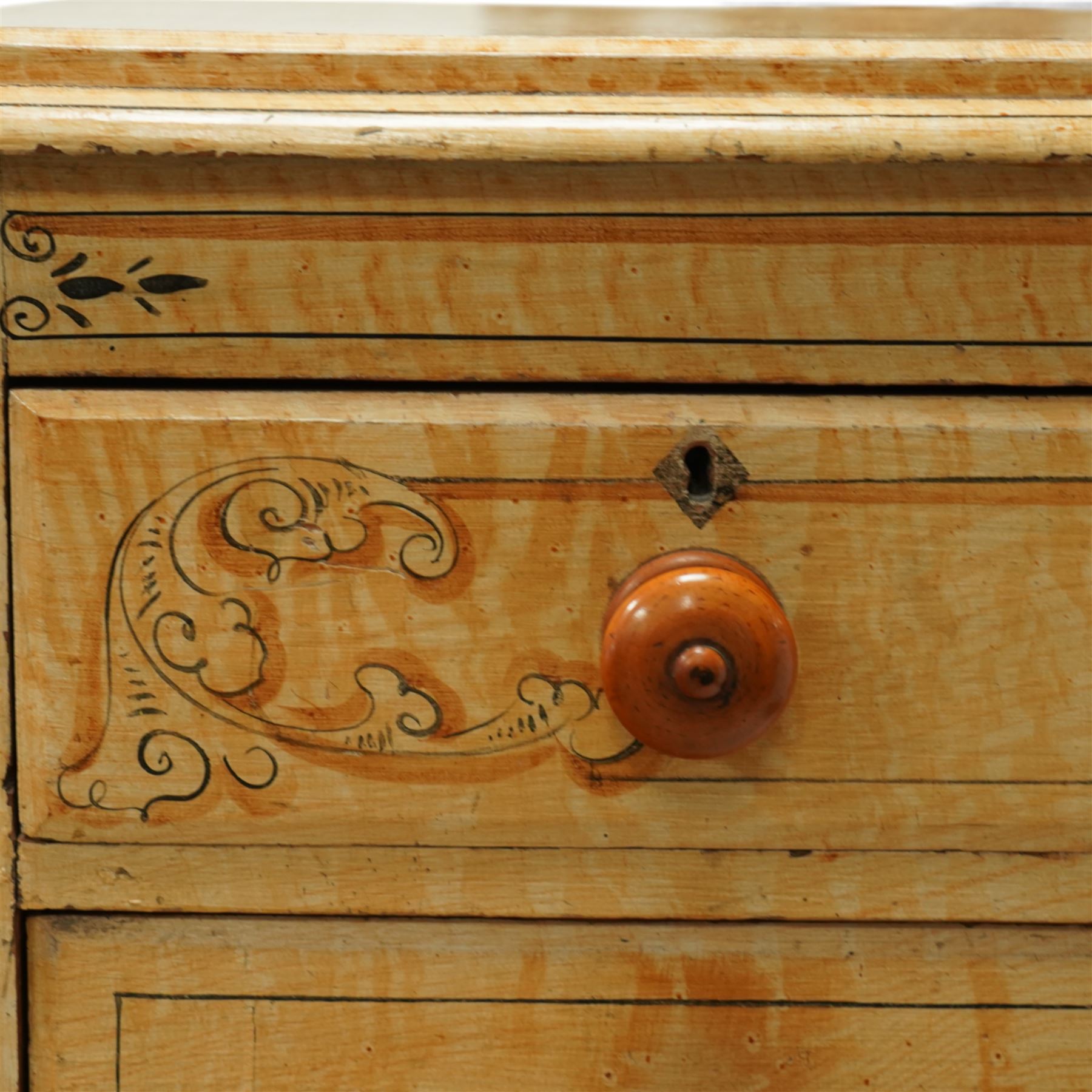 19th century pine painted chest of drawers, rectangular moulded top above two short and three graduated long drawers, each with painted foliate scroll and line detailing, turned knobs, and concealed turned feet, the sides with rounded corners and ebonised detail