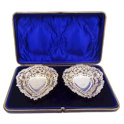 Pair of Victorian silver bonbon dishes, each of heart shaped form with pierced sides and C scroll and flower head rim, upon three ball feet, hallmarked William Henry Leather, Birmingham 1895, contained within a fitted case with blue velvet and silk lined interior, approximate silver weight 2.45 ozt (76.5 grams)