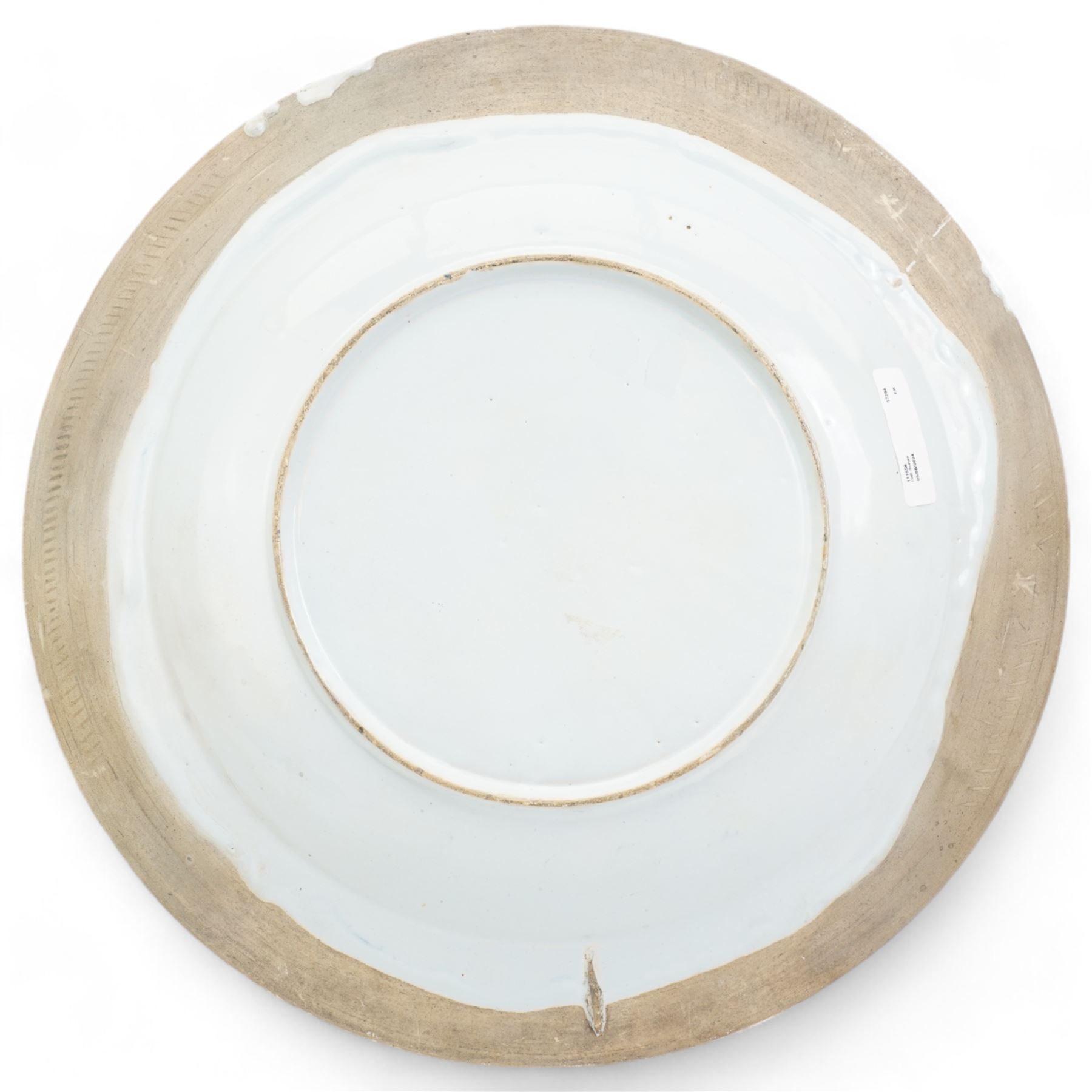 18th century English Delft charger, painted in blue with a Chinese scene with a figure in a boat, another figure crossing a bridge towards a tree and house, within a border of grapes and foliate scrolls, a similar pattern was produced by Delftfield, Glasgow, c.1760, D41cm