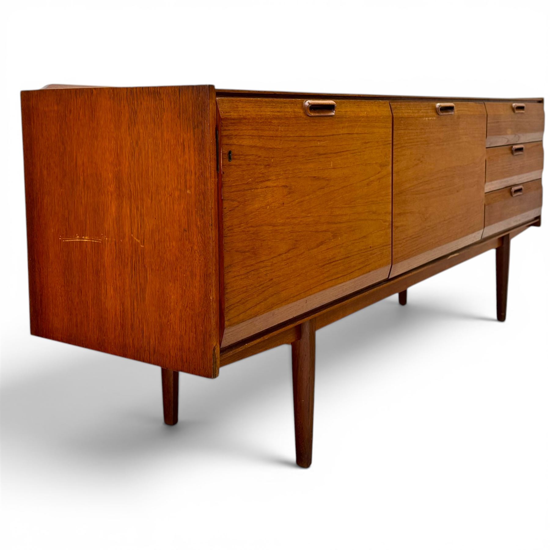 BCM (Bath Cabinet Makers) - mid-20th century teak sideboard, rectangular top with back gallery, left hand side fall front cupboard, centre cupboard opening to reveal a shelved interior, the right side with a bank of three drawers one fitted for cutlery, raised on inset tapering supports