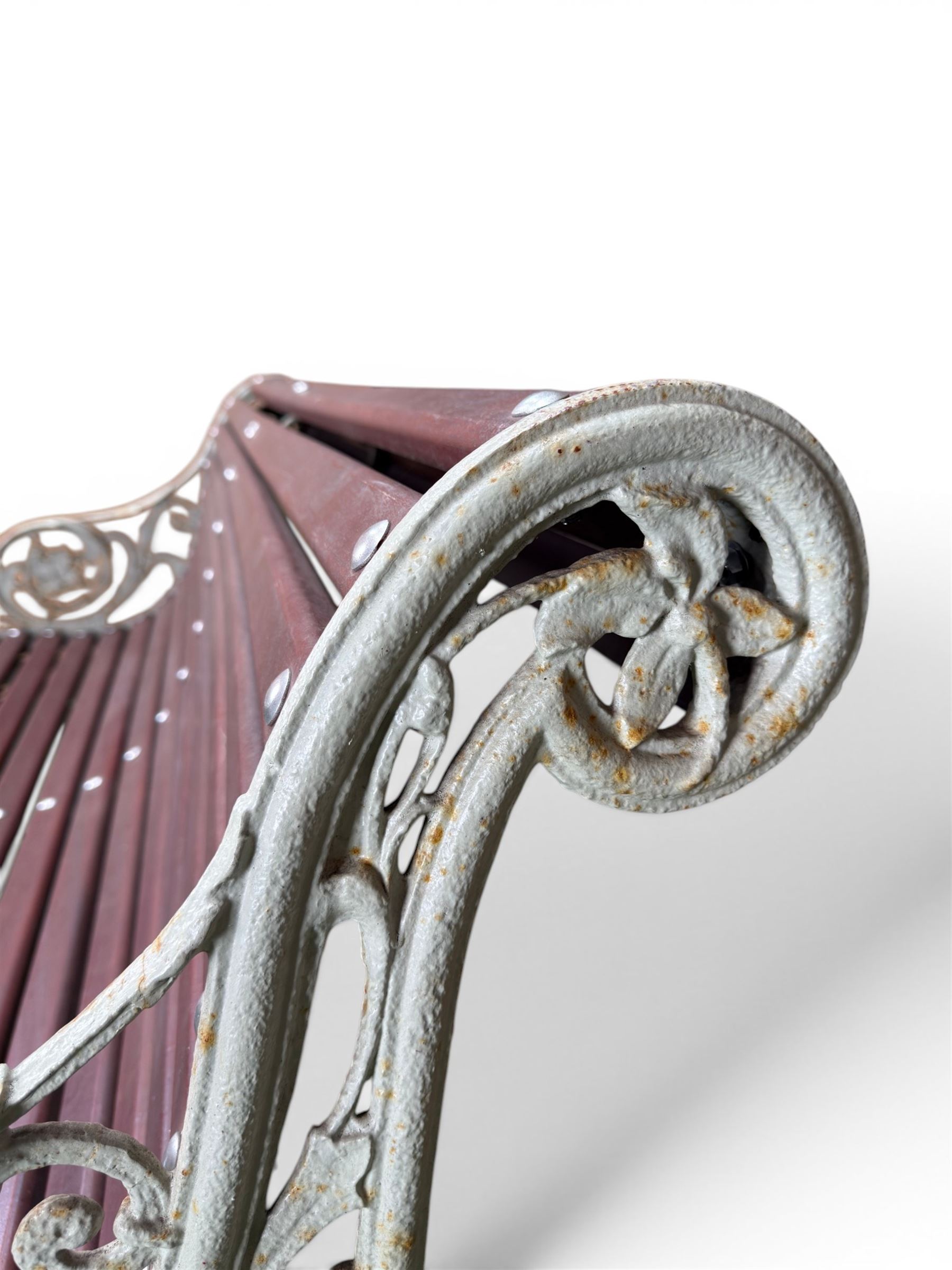 Large late Victorian cast iron garden bench, serpentine form with scroll back and seat, slatted with mahogany stained Sapele