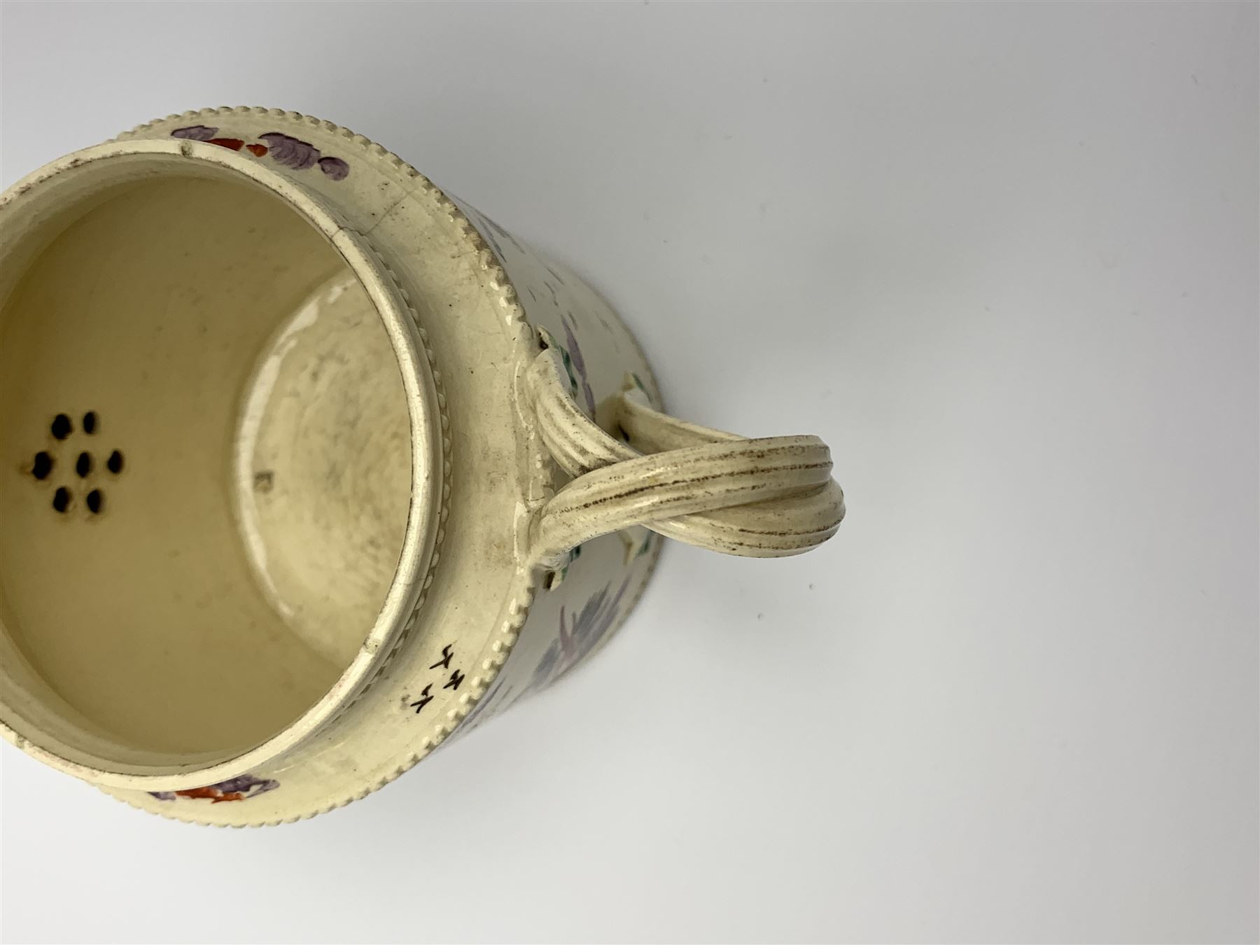 18th century creamware teapot, probably Leeds, with reeded entwined handle and floral finial to the cover, the body with hand painted polychrome decoration of figure to one side, and floral spray to the other, collectors paper label beneath inscribed Leeds Pottery, H11.5cm
