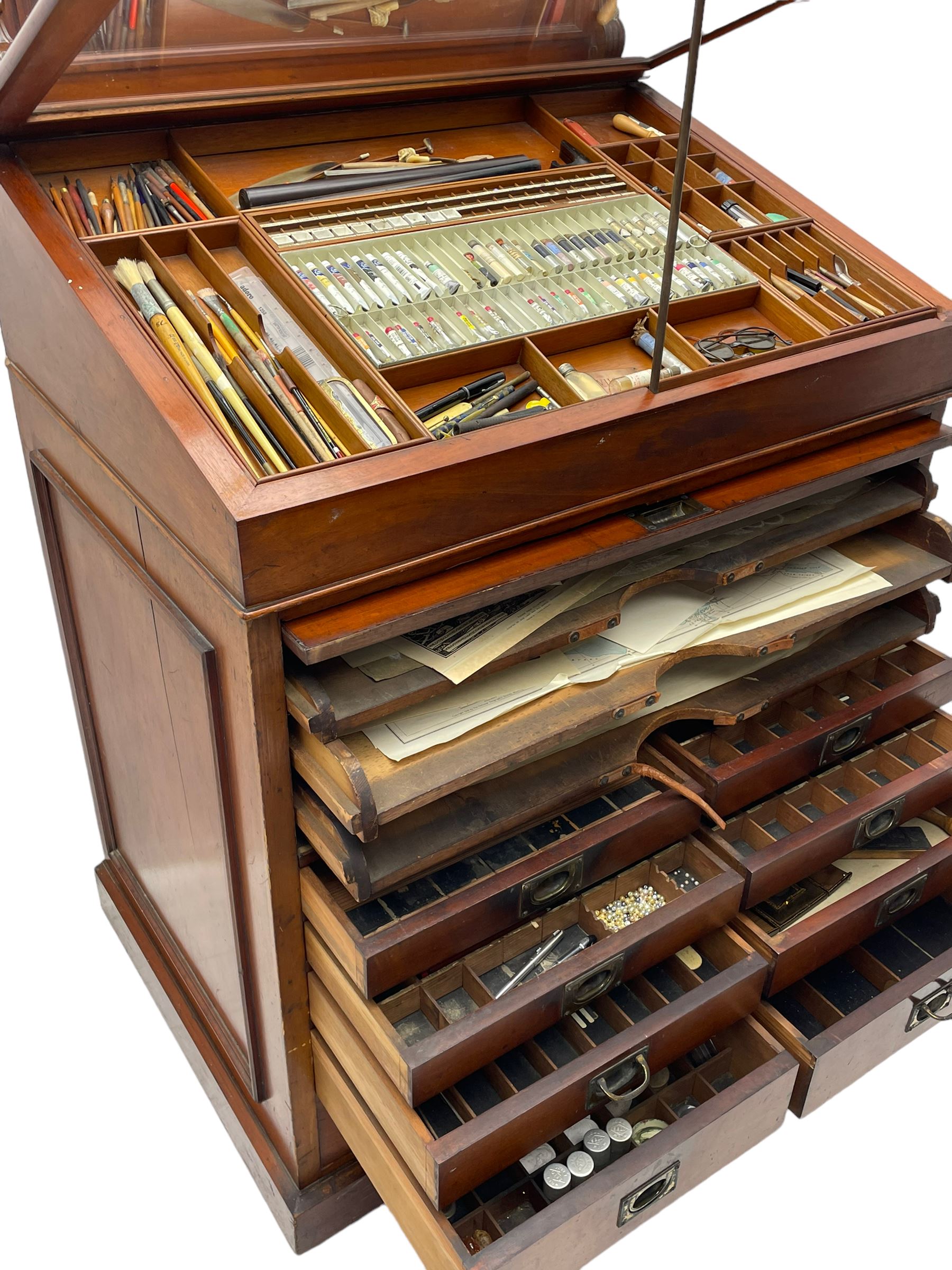 Edwardian mahogany artist's cabinet once belonging to the British artist Eli Marsden Wilson (1877-1965), raised panelled back mounted by carved brackets, sloped and hinged glazed lid enclosing paint holders and compartments, up-and-over panelled door revealing three slides, fitted with two banks of five graduating drawers with recessed brass handles, on skirted base.

Together with a quantity of artists' equipment and tools including paints, paintbrushes, charcoal, chalks, etc. and various prints relating to the life of the artist, including Quaker anti-war posters, Victorian Stevengraphs, and various chromolithographs 

Provenance: Removed from the studio of Eli Marsden Wilson. The cabinet comes to us for sale through family descent. The vendor is descendant of Marsden. Many further etchings removed from the cabinet are being sold in the Spring Art Sale, Friday 15th March 2024, Lots 265-271.

Notes: born in Ossett, Eli Marsden Wilson was the only son of Alfred Wilson, a foreman beamer, and Emma Marsden, and had five sisters. After studying at Wakefield College of Art, he moved to the Royal College of Art in London, where he became a pupil of Sir Frank Short. He had his first exhibit at the Royal Academy in 1905, the same year he married fellow artist Hilda Mary Pemberton.

A Quaker, vegetarian, and pacifist, he was a conscientious objector in World War I and as such was imprisoned in 1917 for two years. In September 1922 he was commissioned by Princess Marie Louise to produce miniature etchings for Queen Mary's Dolls' House at Windsor Castle; two such etchings are being sold in the Spring Art Sale, Friday 15th March 2024, Lot 265.