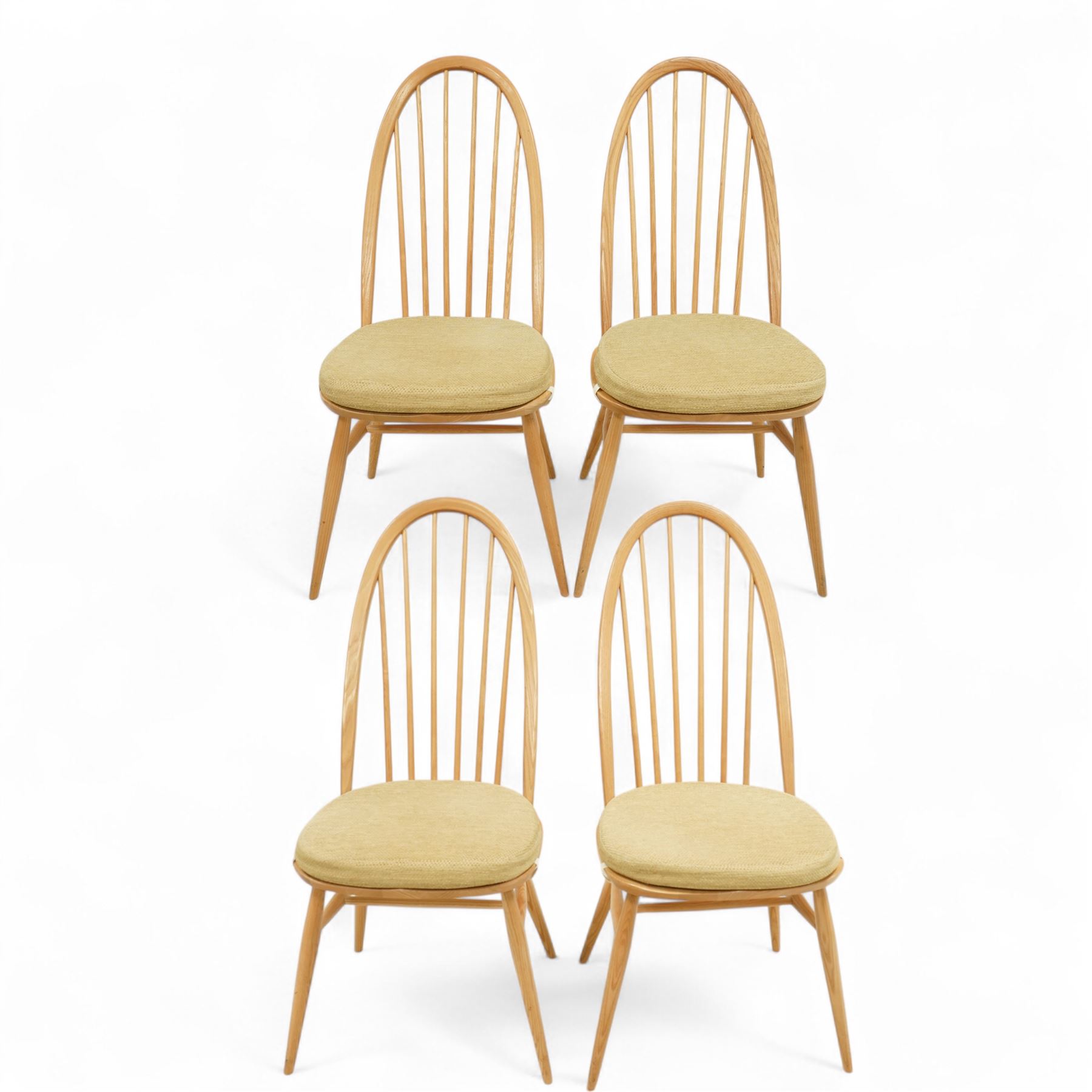 Ercol - light elm set of four Quaker style chairs, high arched backrest with slender spindles, solid wood seat with elasticated strap cushion, on round tapered out swept legs (4)