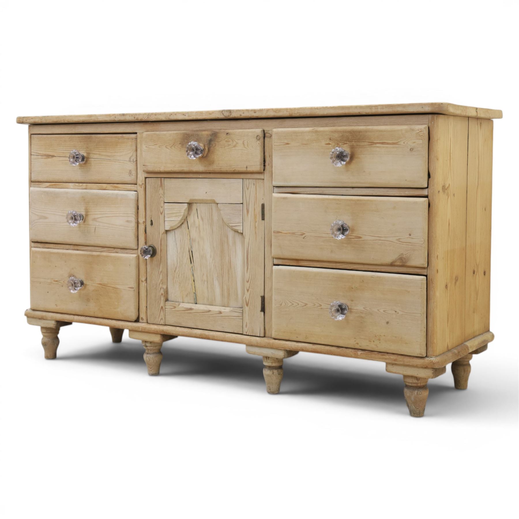 Victorian waxed pine farmhouse dresser, featuring seven drawers with central cupboard, moulded glass handles, raised on turned feet