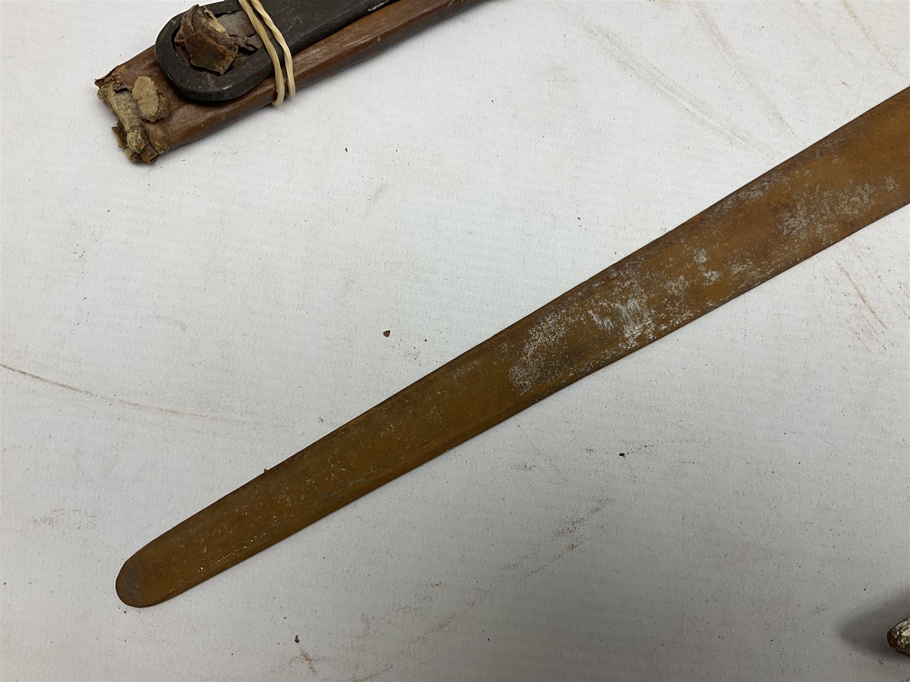 Tuareg Takoba sword with 78.5cm triple fullered blade incised with two crescent moons to either side, metal hilt with stylised floral designs to the cross-guard, decorative grip and disc form pommel cap; in tooled leather scabbard decorated with geometric designs L92cm overall; and an Indian Tulwar sword with 75cm plain curving blade and 'silver' damascened hilt (no scabbard) (2)