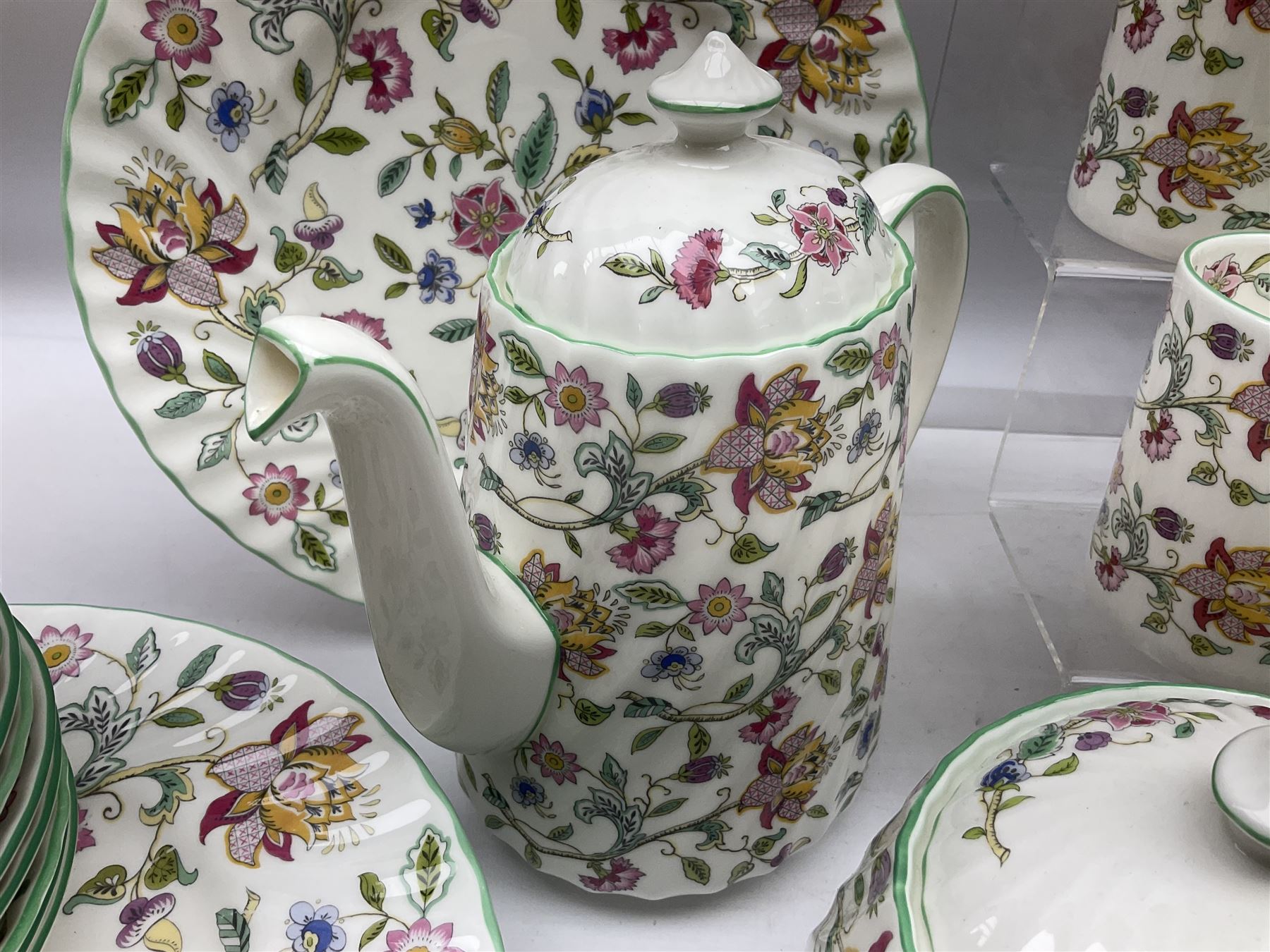 Minton Haddon Hall pattern tea and dinner wares, including basket dish, two covered tureens, six dinner plates, eight dessert plates, twelve tea plates, six soup bowls, six cereal bowls, teapot, coffee pot, milk jug, covered sucrier twelve tea cups and saucers, six mugs, footed bon bon dish, pair of candlestick holders, cake knife and slice etc (81)