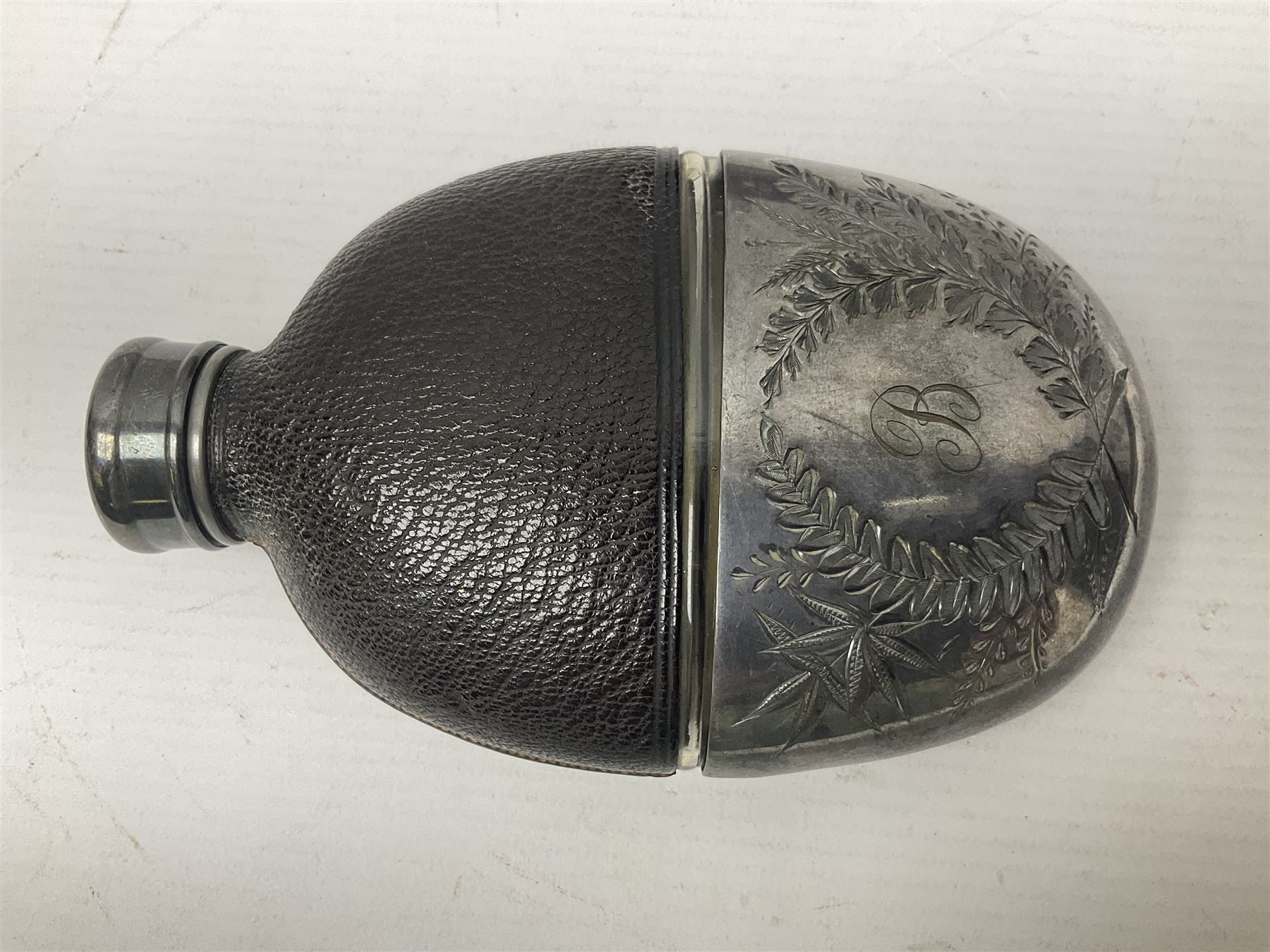 Silver plated glass and pressed leather hip flask, with swivel cap and removable cup, together with a similar oval example, engraved with wreath and initial B, tallest H16.5cm