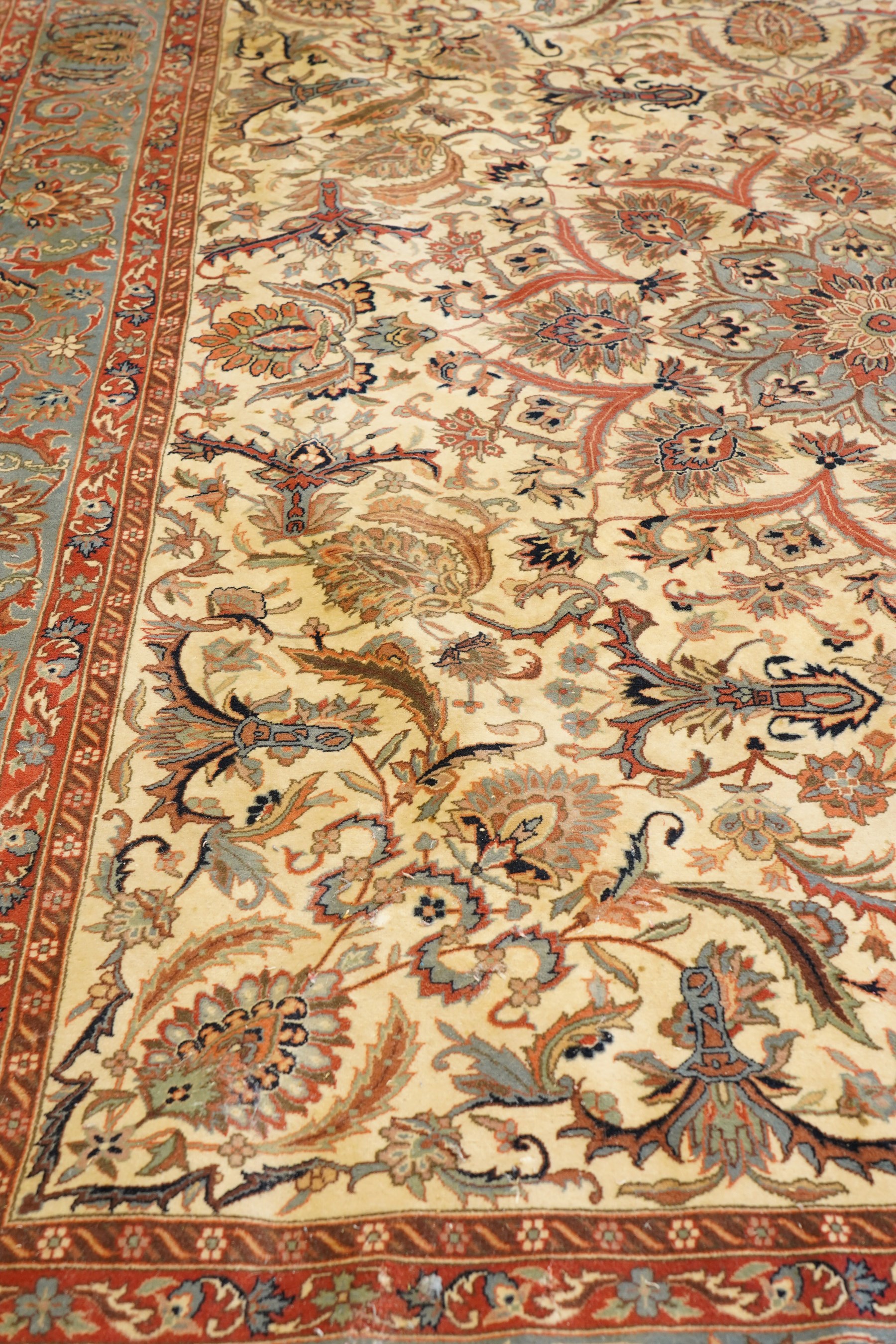 Persian Isfahan ivory and crimson ground rug, the busy field with central floral pole medallion surrounded by foliate motifs and stylised palmettes, the indigo guard line with repeating scrolling plant motifs