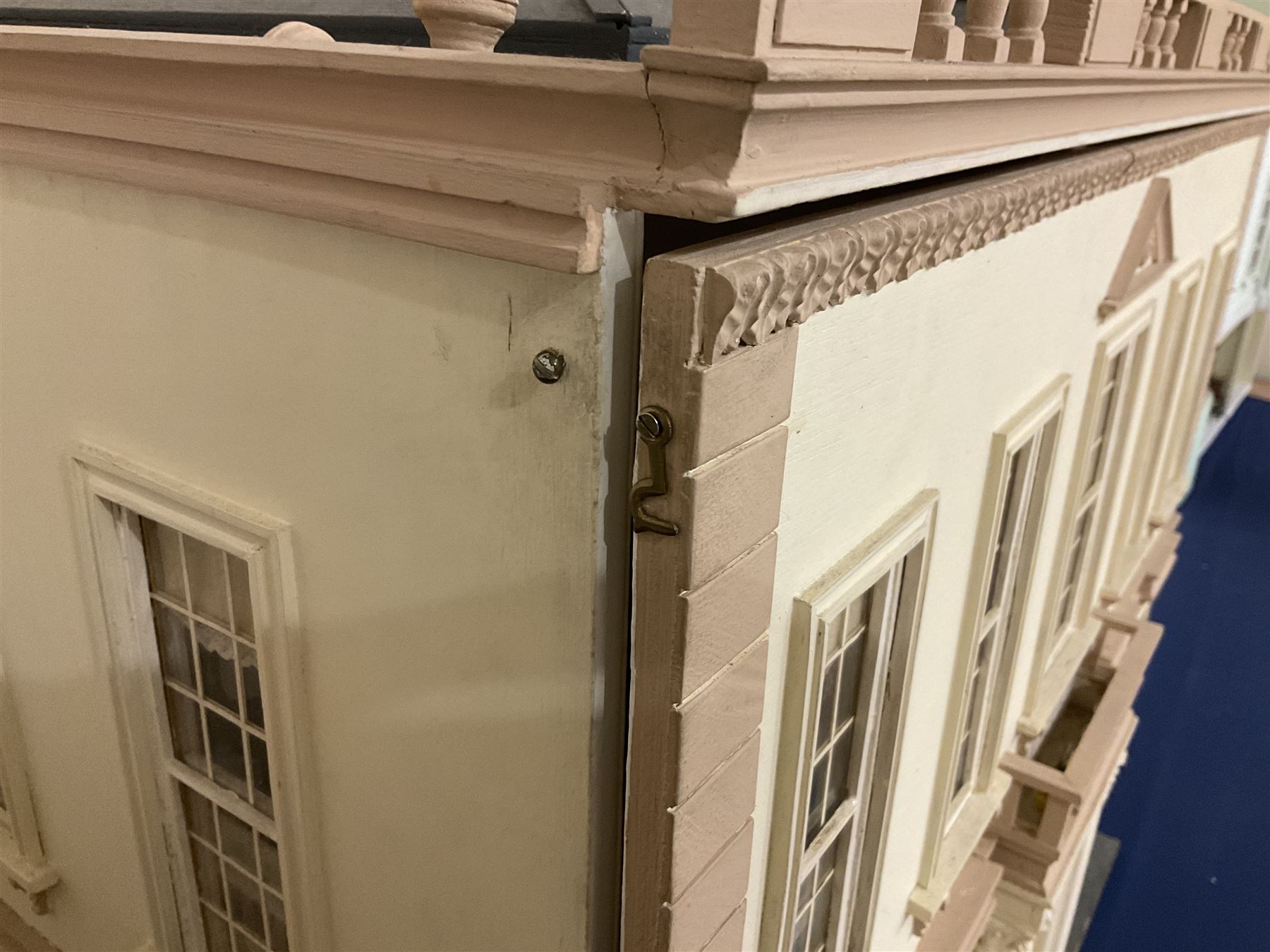 Kit-built wooden dolls house, possibly by Honeychurch, as a 19th century style double fronted two-storey residence; with stucco walls and flat roof with circular skylight and parapet with balusters; central door with fanlight, Corinthium columns and balcony over; simulated sash windows to three sides; hinged front facade opening to reveal a partially furnished interior with central hall, stairs and landing, two ground floor rooms and two first floor en suite bedrooms; wired for electric lighting W69cm H70cm D41cm