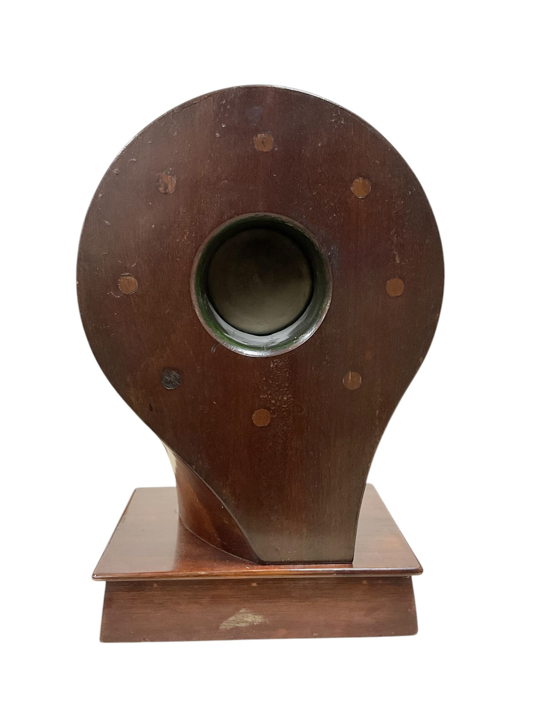 1920's-Aviation clock, mahogany case configured from part of an early 20th century aeroplane propellor, mounted on a conforming plinth with a shaped base, bolt holes filled with brass studs and fitted with an 8-day American spring driven Ansonia insertion movement with a porcelain dial, Arabic numerals, spade hands and seconds dial. Wound and set from the rear.