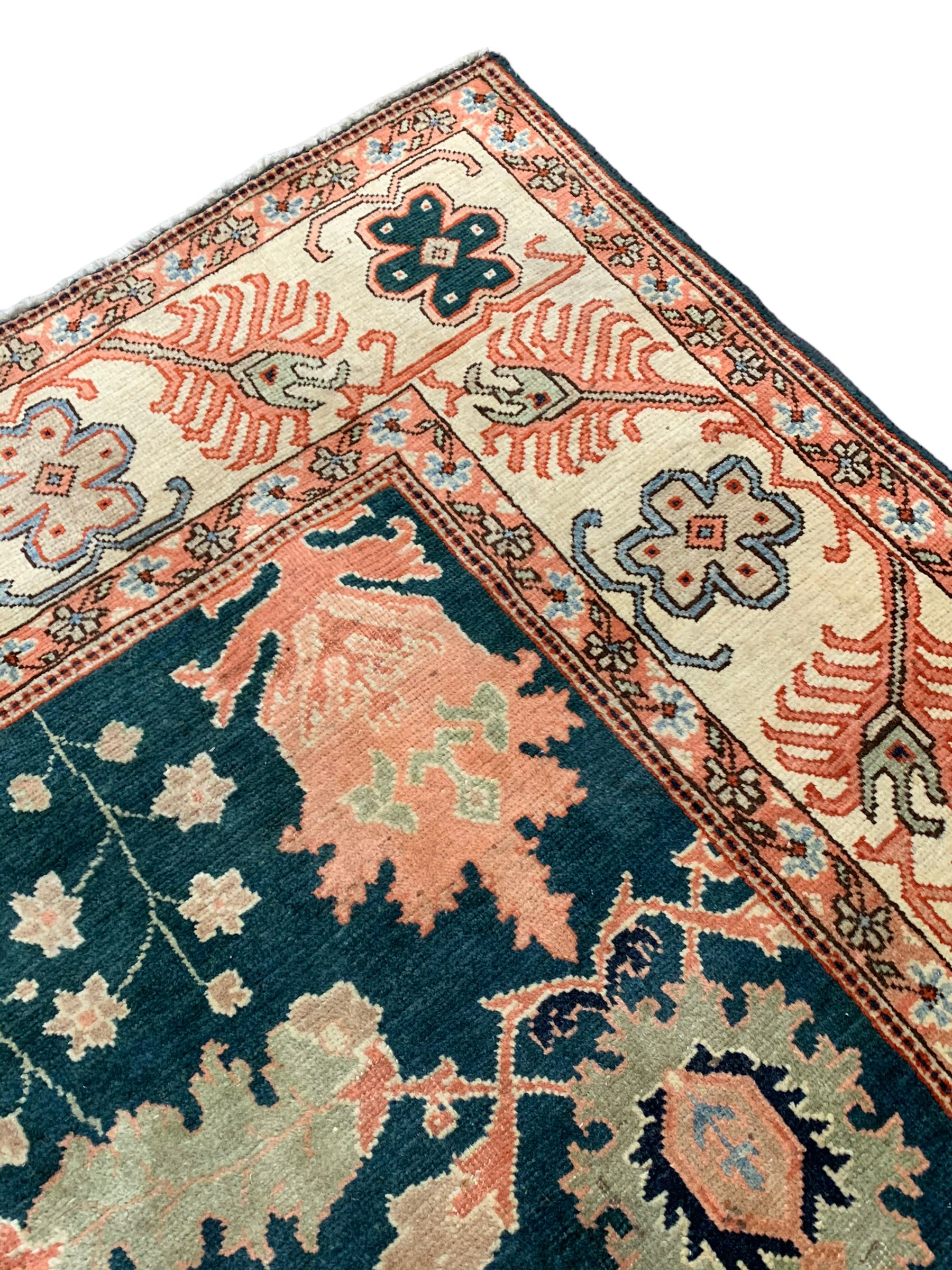 Persian emerald green ground rug, the field decorated with large stylised plant motifs, ivory ground border with repeating leaf motifs, the guards decorated with trailing branch and flowerhead motifs