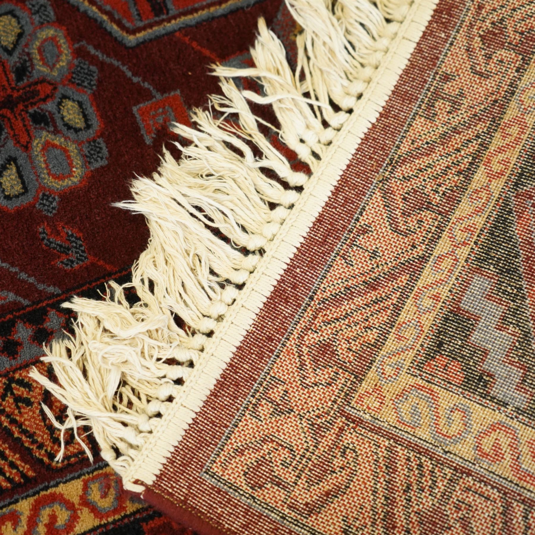Persian Karabagh design rug, red madder field with three linked octagonal medallions surrounded by floral geometric motifs within multiple stylized borders 
