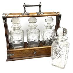 A Mappin & Webb silver plate mounted oak tantalus, containing three square sided cut glass decanters, complete with key, H35cm, together with a further square sided decanter. 