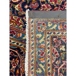 Central Persian crimson ground Kashan carpet, shaped floral medallion surrounded by trailing foliate branch and stylised plant motifs, repeating scrolling border decorated with further floral motifs