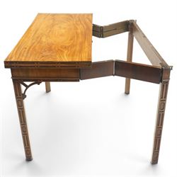George III Chippendale design mahogany table, the rectangular hinged top with geometric carved edge, opening to reveal a baize-lined interior supported by twin concertina rear gateleg supports, over a banded frieze and pierced C-scroll spandrels, the inner chamfered square supports carved with geometric blind-fretwork detail