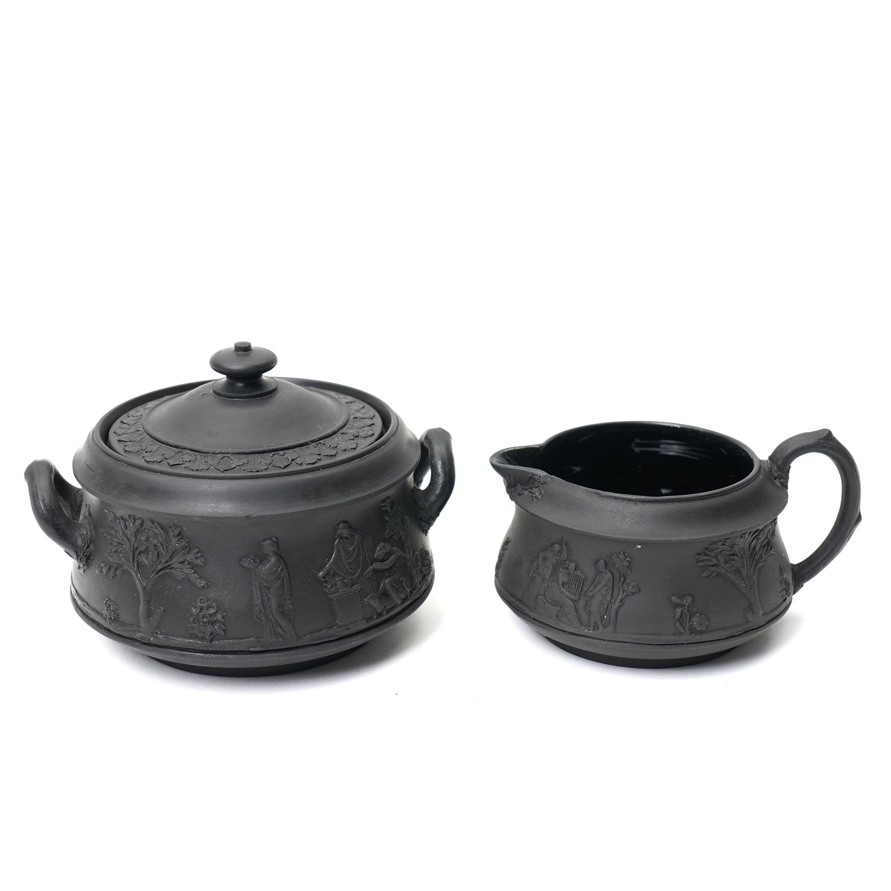 Four pieces of 19th century Wedgwood black basalt ware, c.1875, comprising larger and smaller jug, covered sucrier and teapot, each decorated with classical scenes in high relief, larger jug H13cm