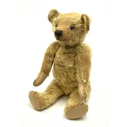 1930s teddy bear, possibly Farnell, with wood wool filled blond mohair body, the revolving head with original clear glass eyes, shaved muzzle with vertically stitched nose and mouth and jointed limbs with five-stitch claws H18.5