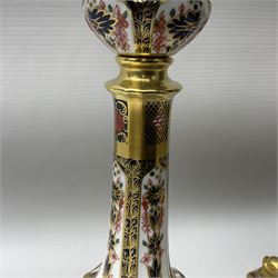Pair of modern Royal Crown Derby Old Imari 1128 pattern candlesticks, each with shaped drip tray affixed to squat socket, upon spreading stem and canted square base with gilt dolphin edges, with printed marks beneath including Roman numeral year cypher for 2003, H26.5cm, with original boxes