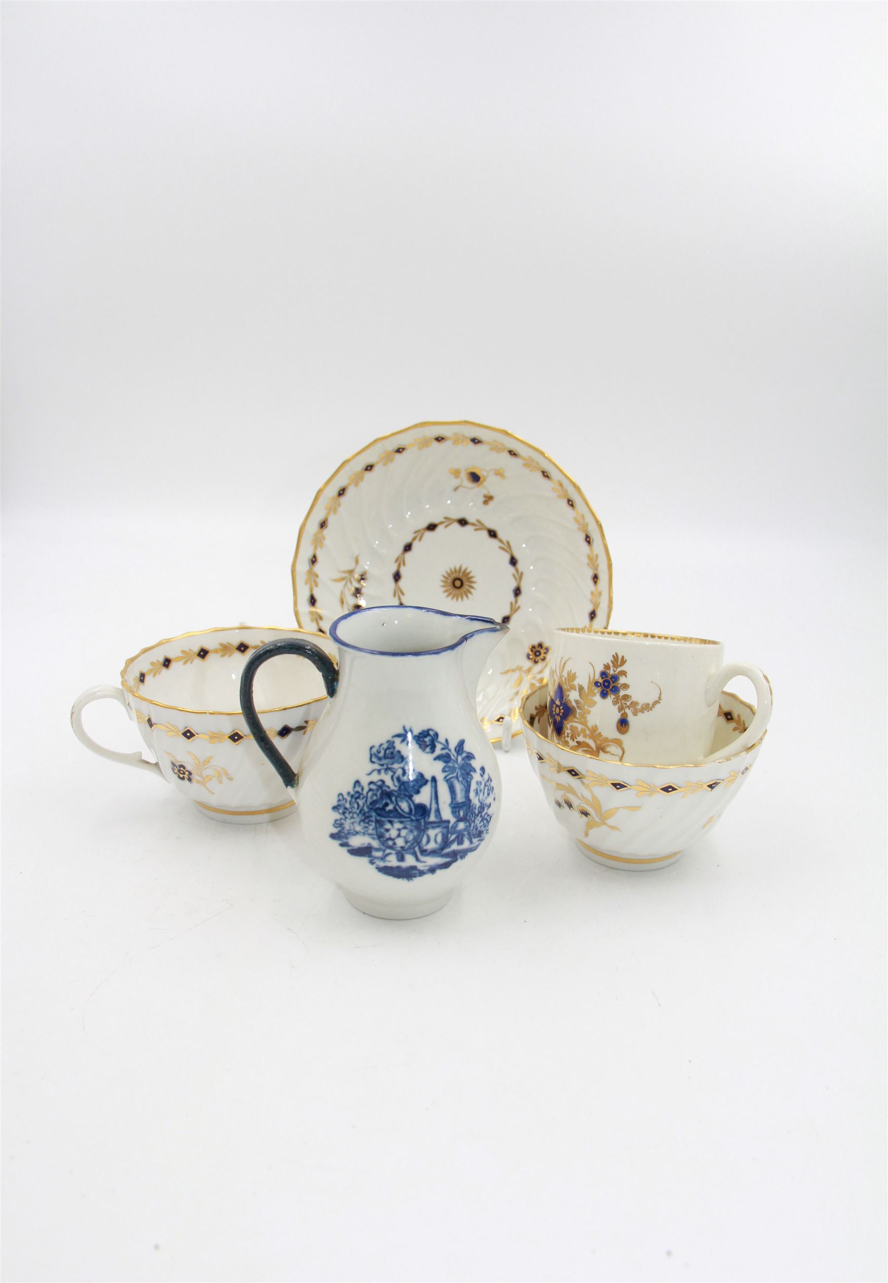 18th century Caughley blue and white sparrow jug, decorated in the Mother and Child pattern, circa 1780-1790, with underglaze C mark beneath, H9cm, together with a Worcester coffee cup, circa 1785 painted with floral sprays in underglaze blue and gilt, with crescent mark beneath, and a Caughley trio of tea cup, tea bowl and saucer, each of moulded wrythen fluted form and decorated with gilt and blue sprigs and bands, each with crescent mark beneath, (5)