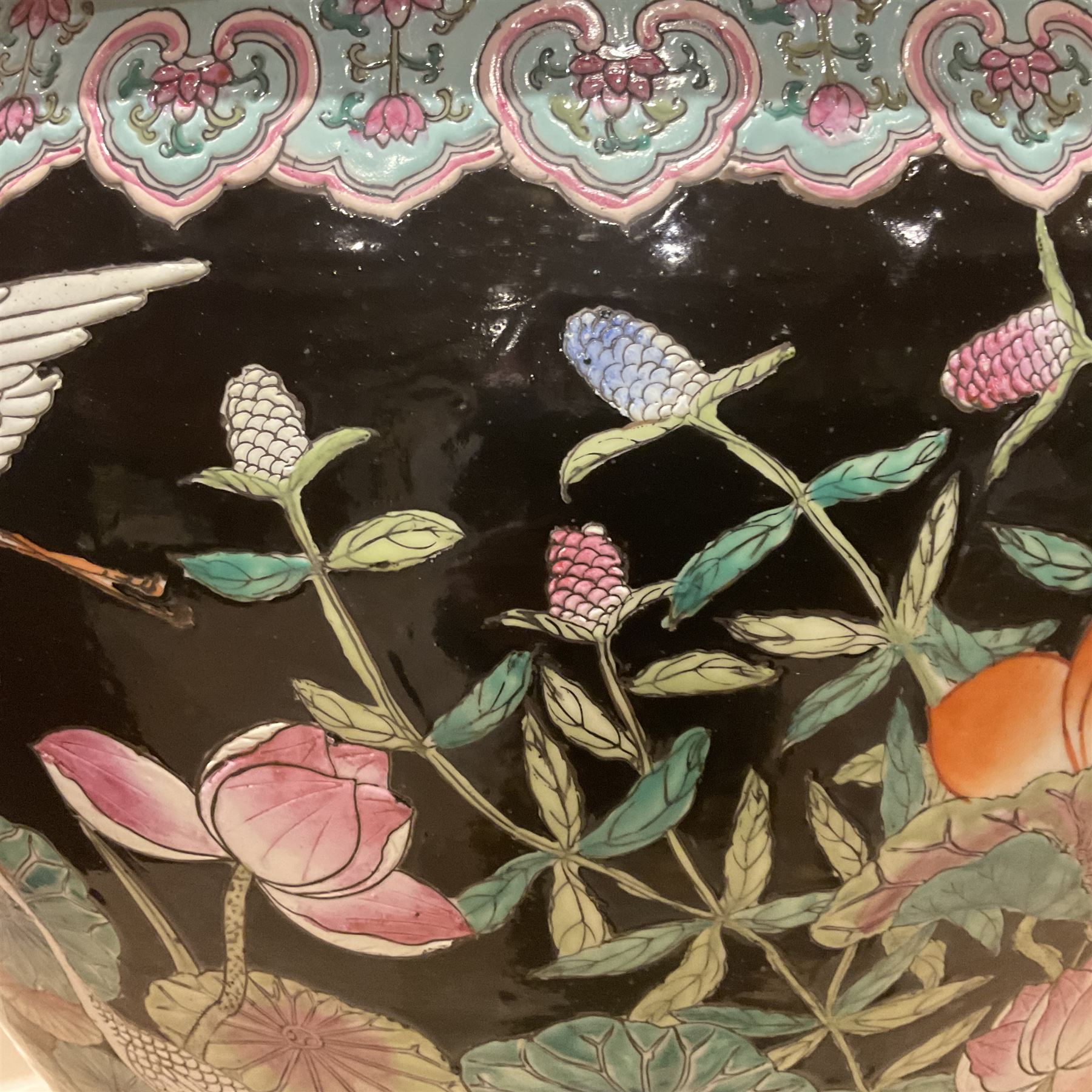 Large 20th century Chinese famille noir glazed porcelain jardinière, of ovoid form, the exterior enamelled with butterflies and white cranes amidst blossoming water lilies and pads against a black ground, between two stylised polychrome borders and beneath a key border to rim, the interior enamelled with red koi fish swimming amongst water fronds and weeds, with printed red character mark beneath, the whole upon an ebonised hardwood stand with three cabriole legs, jardinière H42cm D47cm, including stand overall H69.5cm