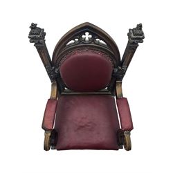 Late Victorian Gothic-revival armchair, arched crest rail carved with tracery and trefoil detail, padded circular back and seat, brass studded burgundy leather upholstery, shaped armrests with scrolled terminals, on square tapering supports