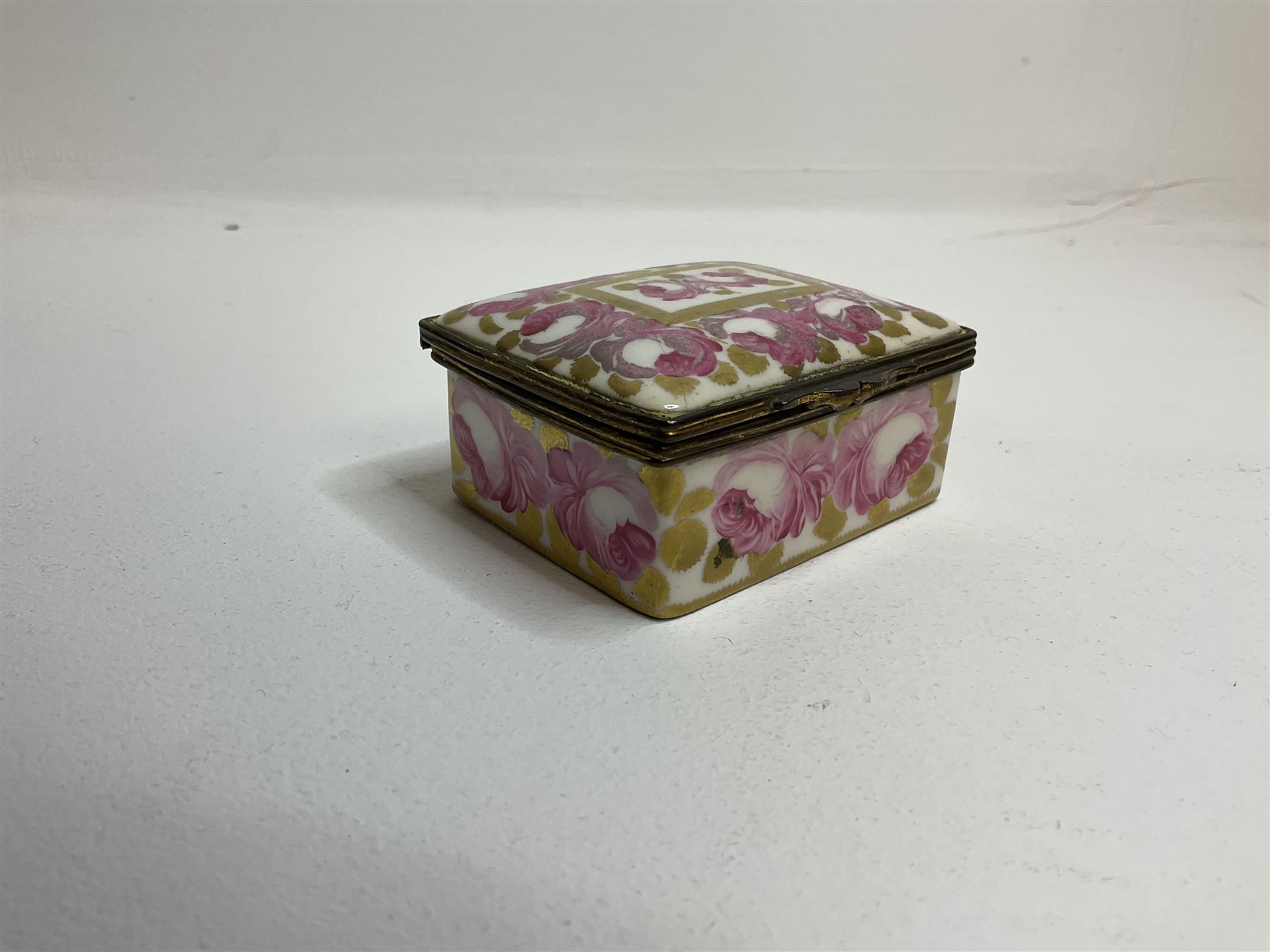 Early 19th century Swansea box of rectangular form, densely decorated with painted pink cabbage roses and gilt foliage upon plain ground, the hinged lid opening to reveal interior painted with two further roses upon plain ground, marked Swansea. in gilded lettering beneath, W7cm H3.5cm D5.5cm