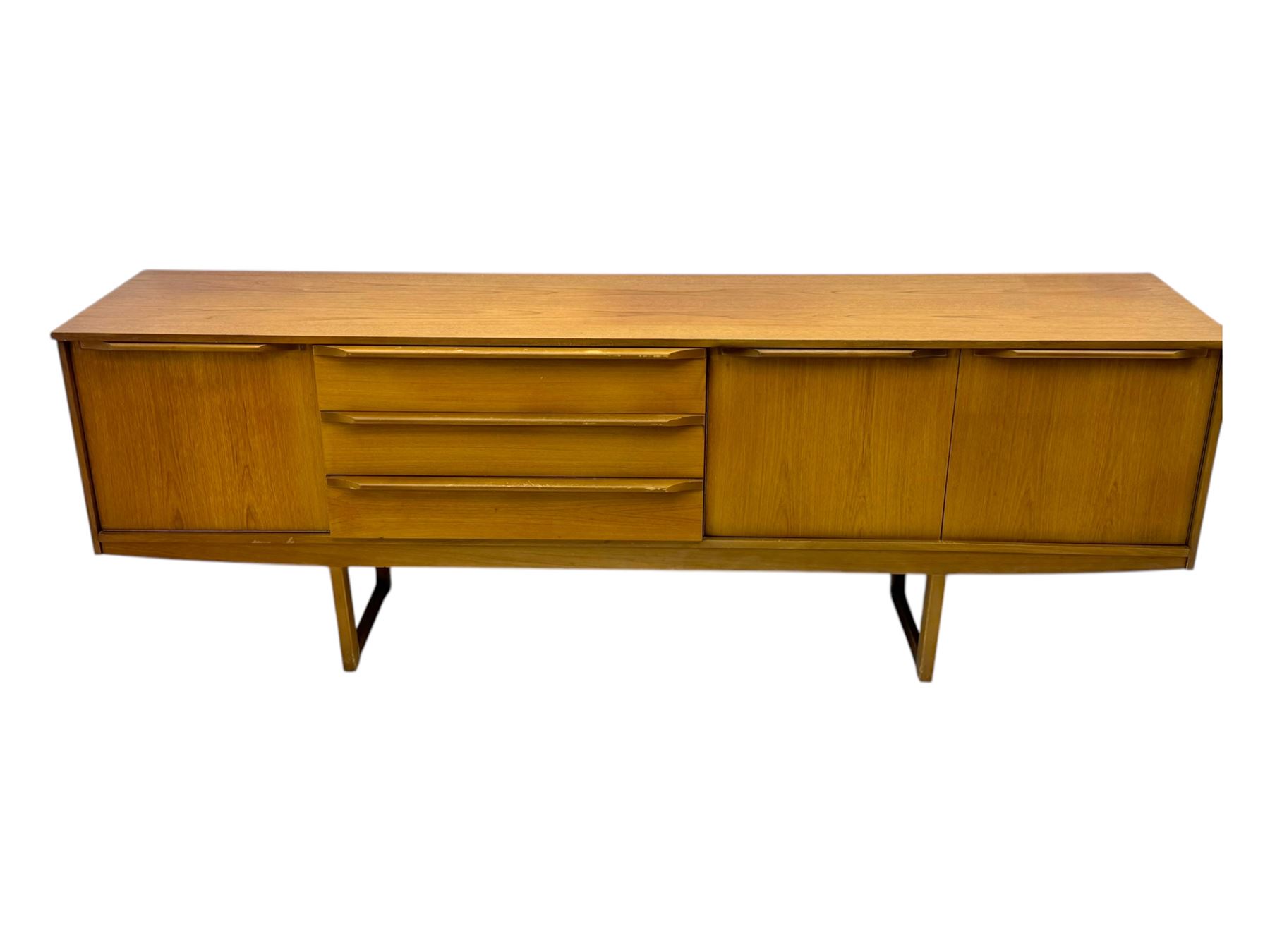 Mid-20th century teak sideboard, fitted with a fall-front cupboard, three drawers including a green baize-lined cutlery drawer, and a double cupboard, with integrated handles, on sleigh supports