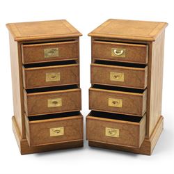 Pair of burr oak bedside tables with campaign brass handles, inlaid and crossbanded top, above four graduating drawers with cockbeaded edges, raised on a plinth base 