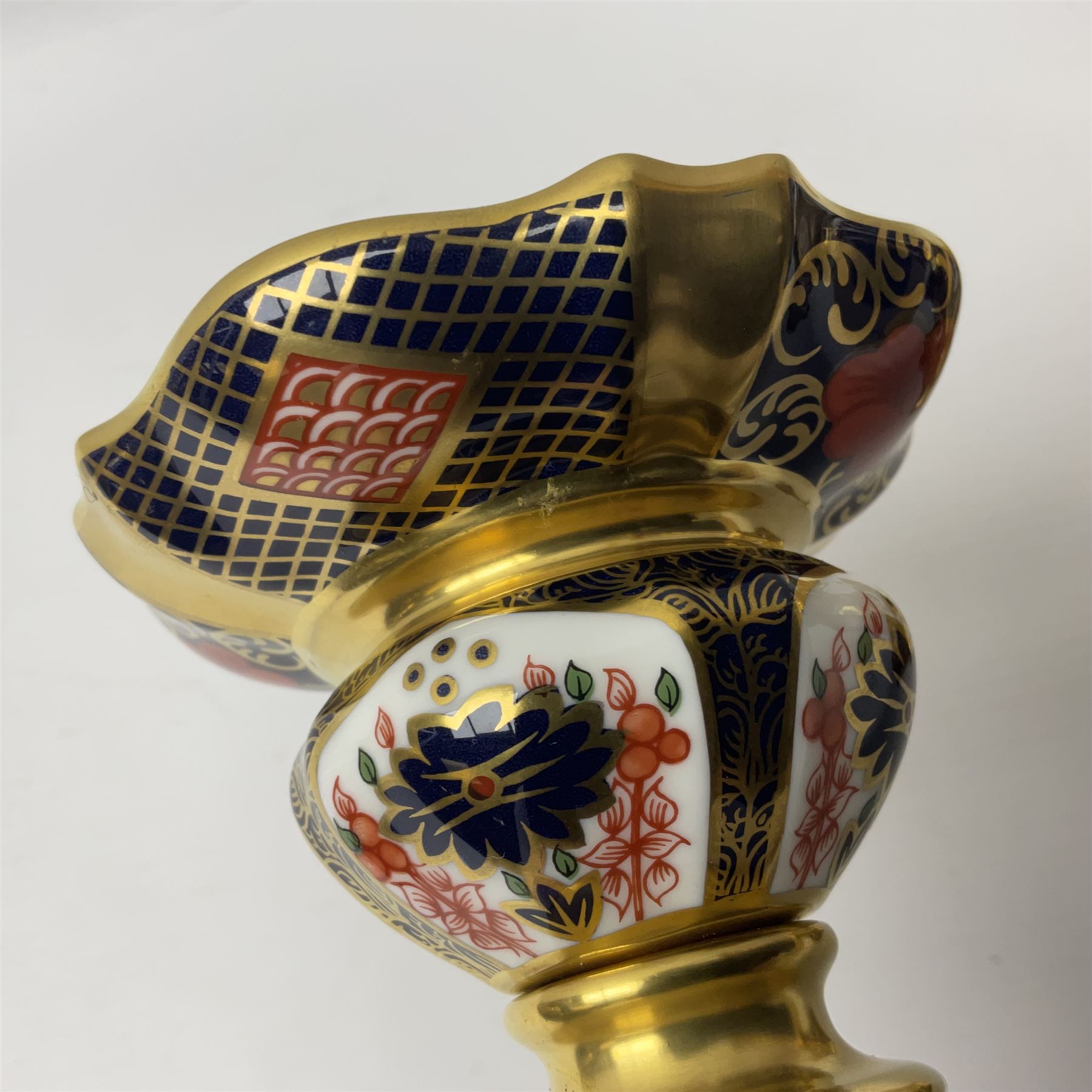 Pair of modern Royal Crown Derby Old Imari 1128 pattern candlesticks, each with shaped drip tray affixed to squat socket, upon spreading stem and canted square base with gilt dolphin edges, with printed marks beneath including Roman numeral year cypher for 2003, H26.5cm, with original boxes
