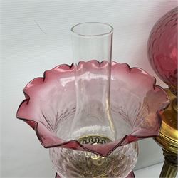 Victorian cast brass oil lamp, with fluted pink glass shade, together with two smaller brass oil lamps with pink shades and reservoirs and a pair of oil lamps, the bases modelled as putti, with pink glass reservoir  and frosted shades, tallest H70cm