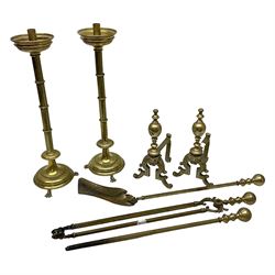 Pair of brass candlesticks, raised upon three lion paw feet, together with fire dogs with lion masks to the front and fire tools 