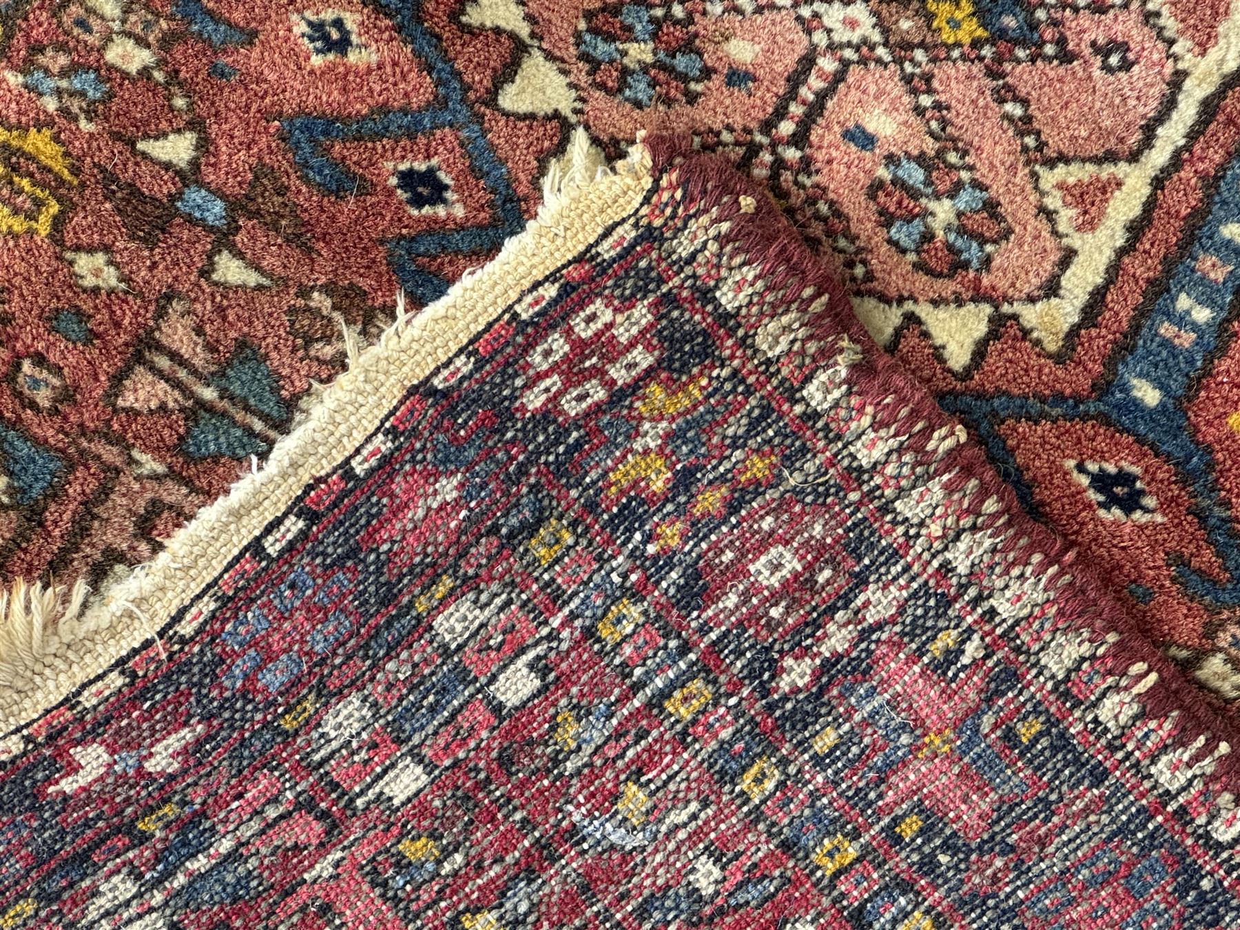 Belgian Sultan woollen ground rug, central navy field densely decorated with floral sprays and geometric patterns (192cm x 135cm); handwoven tribal terracotta ground rug (121cm x 71cm); Persian crimson ground runner, all over stylised floral and foliate motifs (266cm x 94cm)