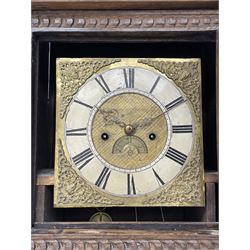 19th century carved oak longcase clock, projecting cornice over guilloche carved frieze, square brass dial with silvered Roman chapter ring and calendar aperture, decorated with ornate mask cast spandrels, the trunk door and base carved with potted plant, twin train driven eight day movement striking on bell