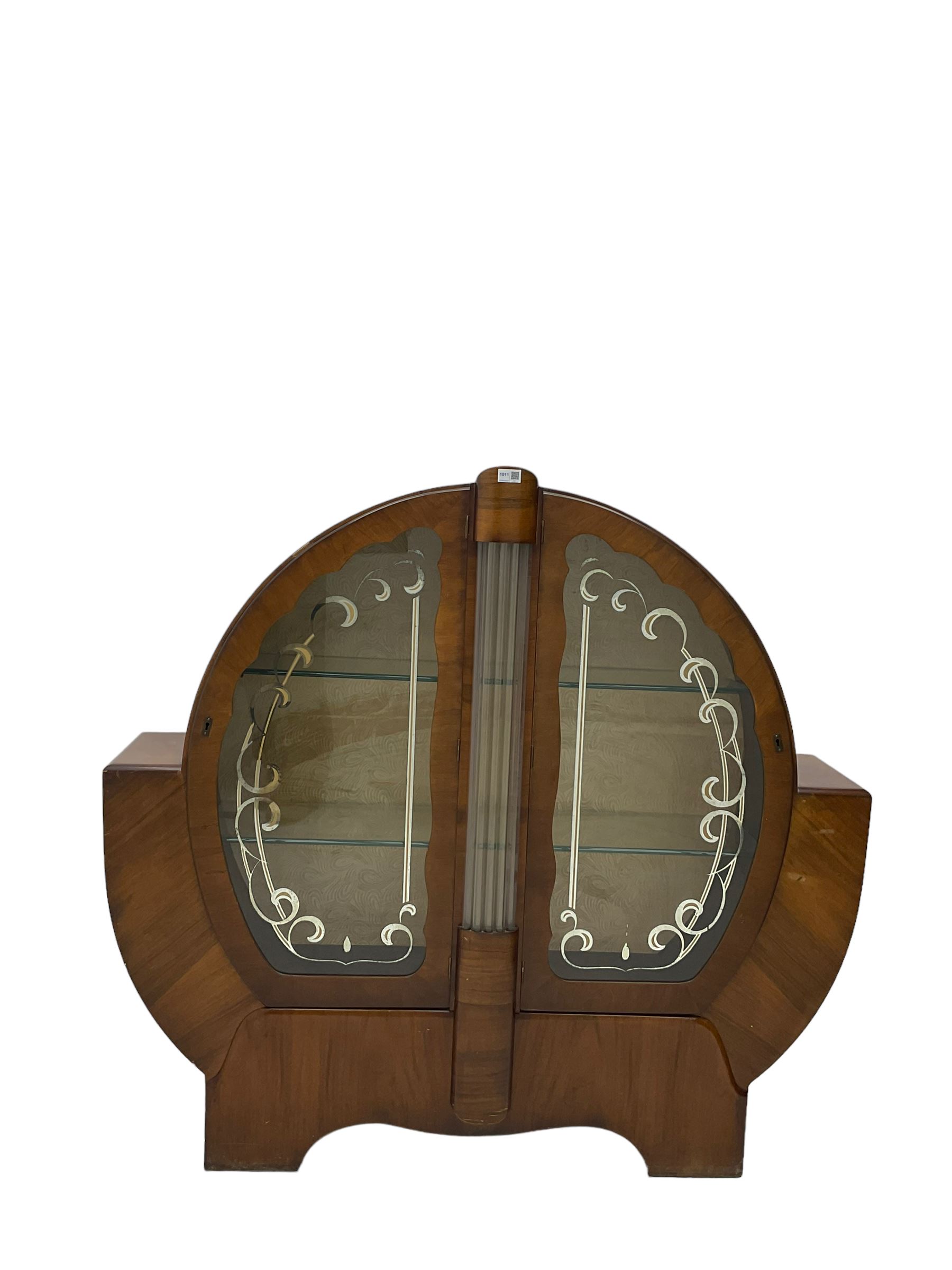 Art Deco walnut display cabinet, of circular design, fitted with two shaped glazed doors enclosing two glass shelves, flanking five glass rods