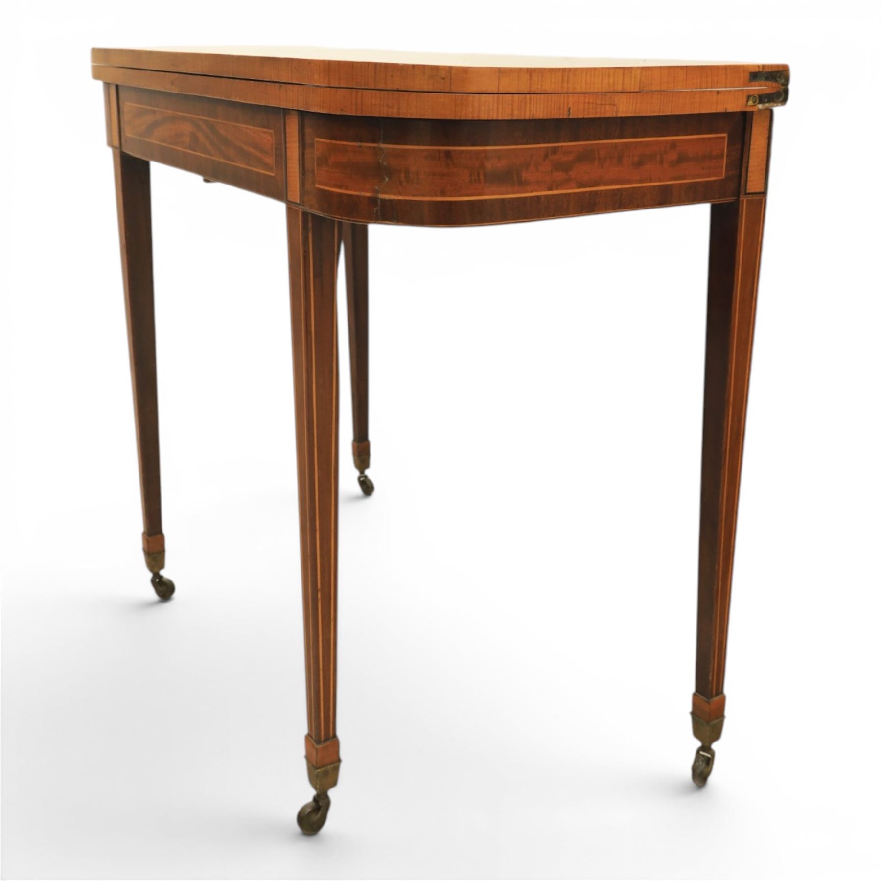 Regency mahogany fold-over tea table, rounded rectangular top with gateleg action, inlaid and crossbanded frieze, raised on squared tapering supports on brass castors