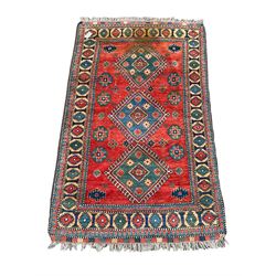 Persian red ground rug, triple medallion to field, decorated with geometric motifs