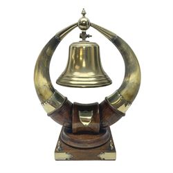 Early 20th century oak and horn dinner bell, the silvered bell suspended from a pair of cow horns, with silver plated mounts and blank shield shaped cartouche, upon square base, H37cm