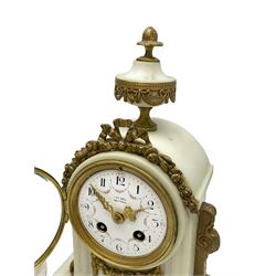 An early 20th century white marble mantle clock in a break front case with an arched top and finial, gilded scroll work to the sides and pierced foliate panels to the front, plinth raised on five bun feet, enamel dial with garland decoration, Arabic numerals, minute markers and Louis XV gilt hands, within a convex glazed bezel, eight-day Parisian striking movement striking the hours and half hours on a bell, with two conforming single light candlesticks. With Pendulum.

