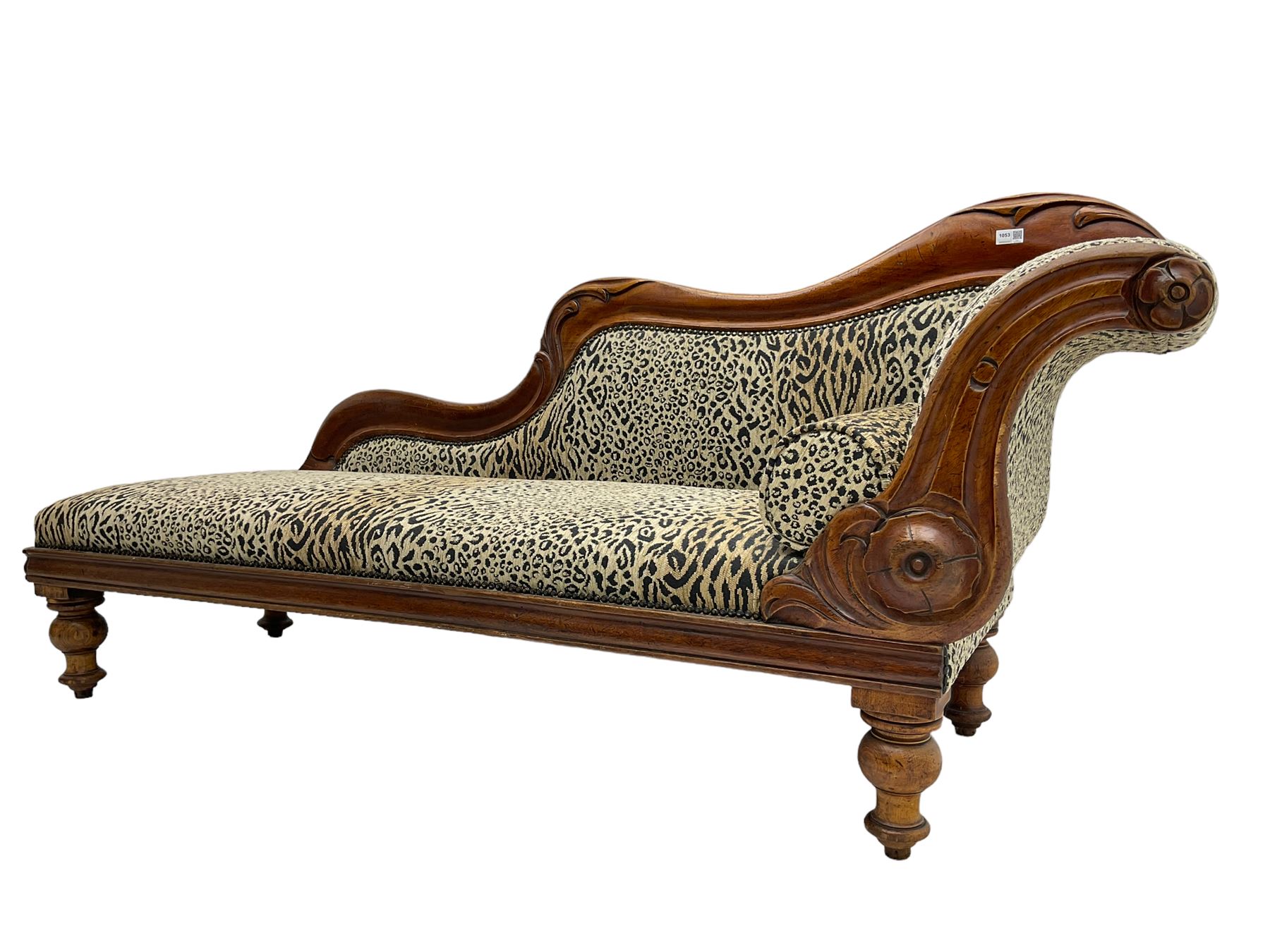 Victorian mahogany framed chaise longue, shaped arm carved with acanthus leaves, the scrolled back with applied carved rosettes,upholstered in monochrome leopard print fabric with bolster cushion, raised on turned supports